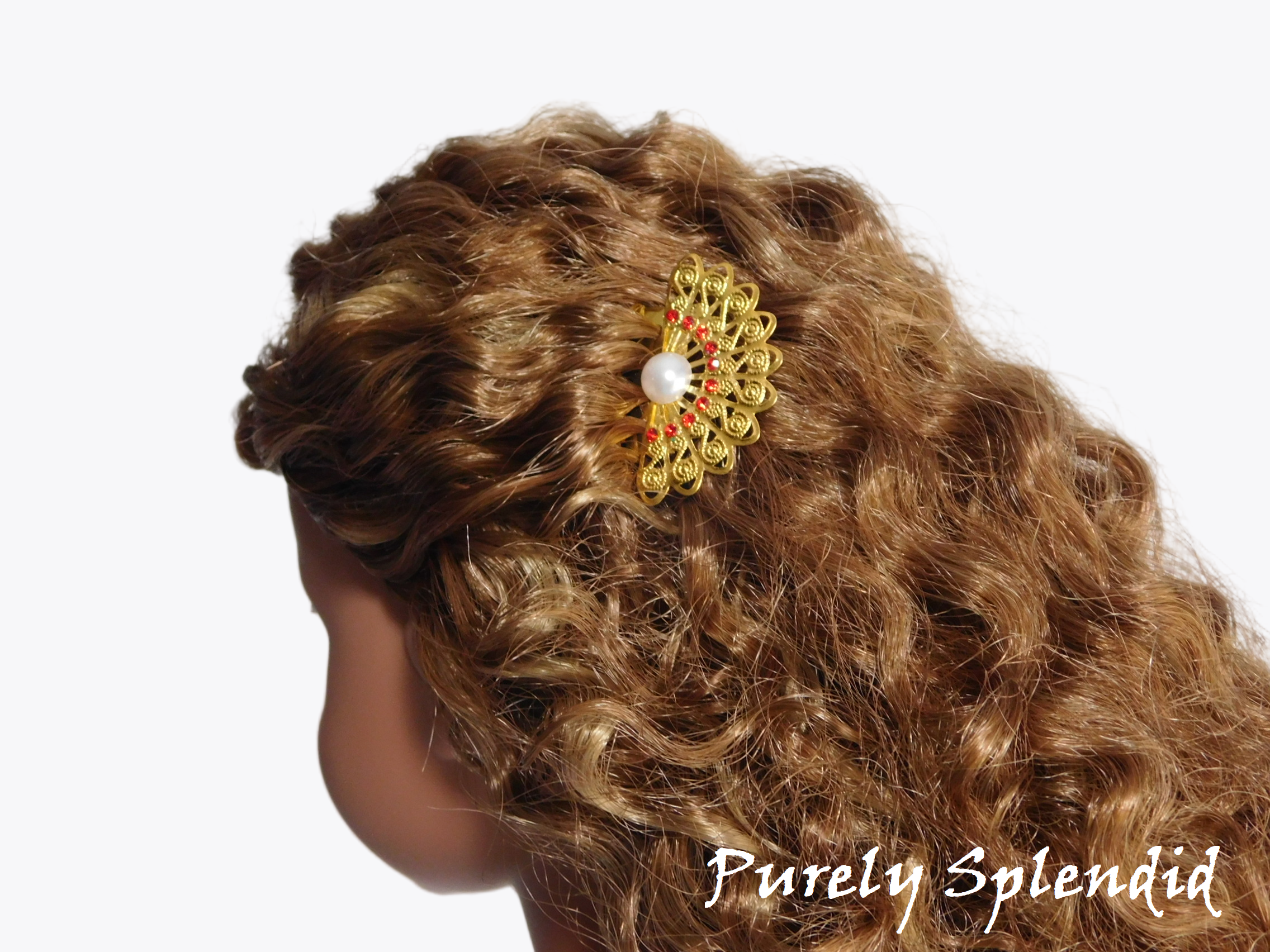 doll wearing a gold filigree fan with red rhinestones and a pearl center hair comb