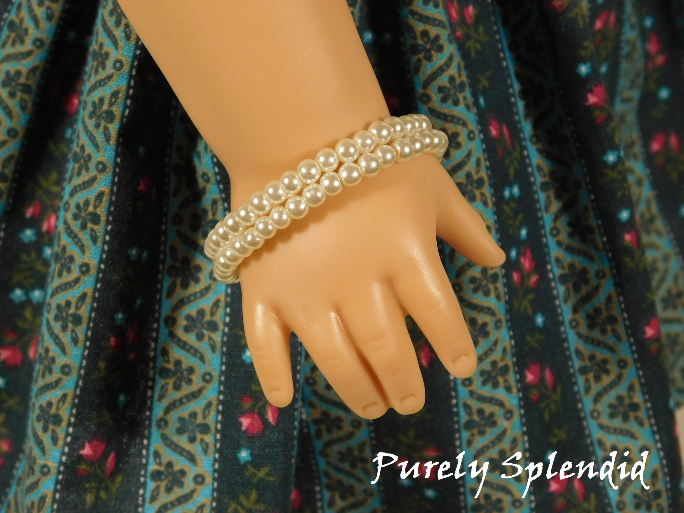 two single row pearl stacking bracelet worn by an 18 inch doll
