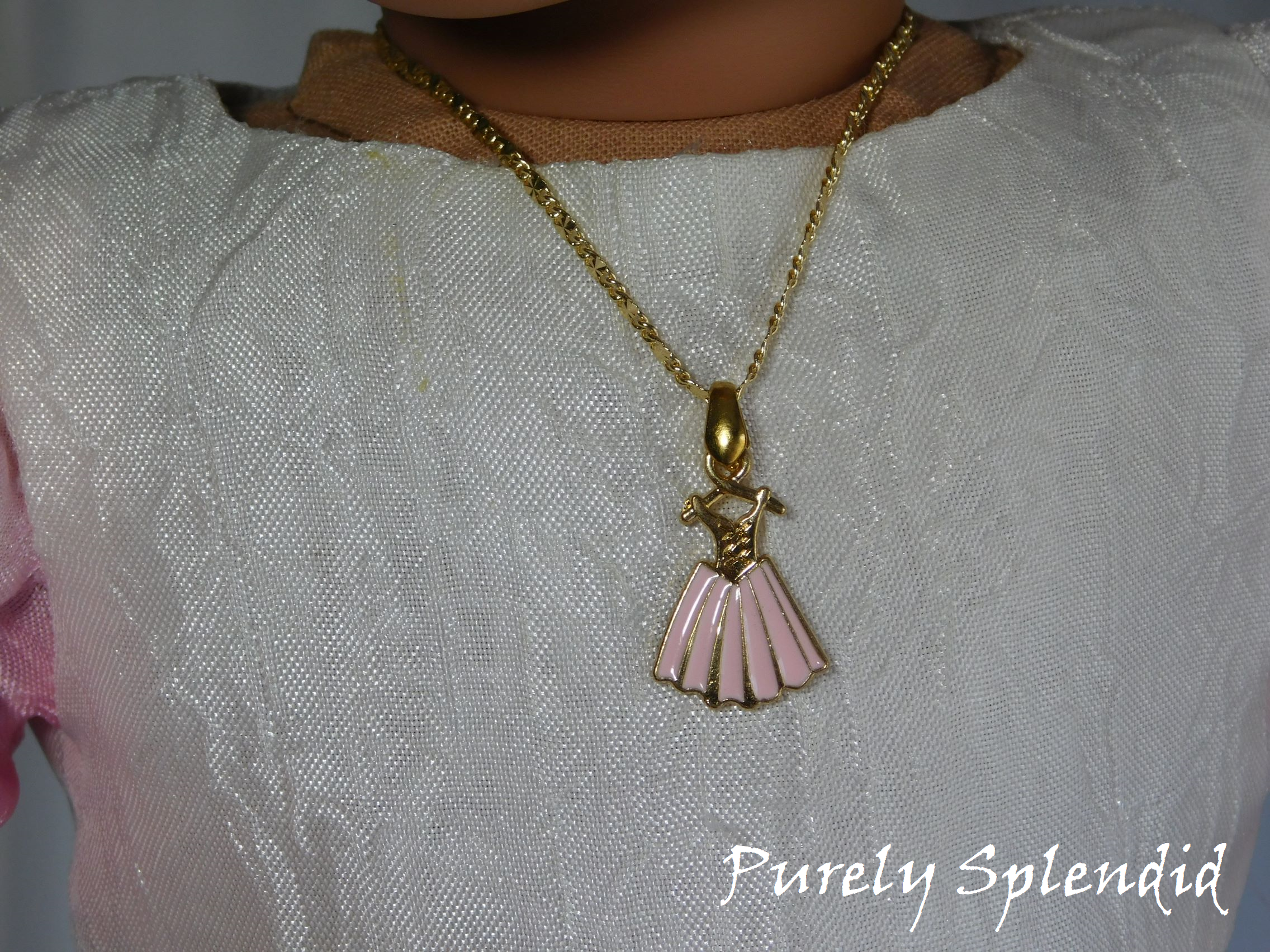 pink dress necklace on a dainty gold chain worn by an 18 inch doll