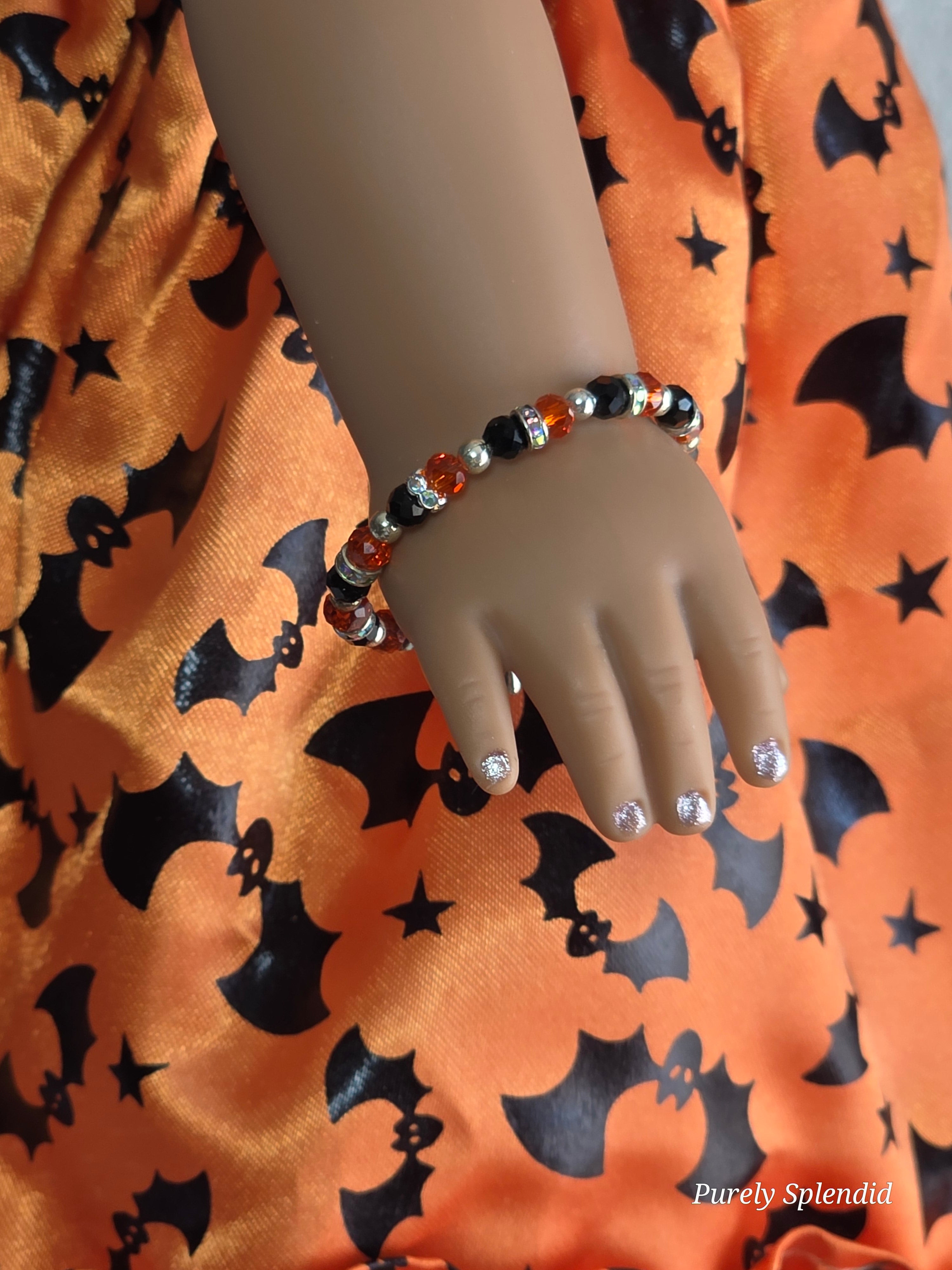 sparkling orange and black Halloween bracelet worn by an 18 inch doll