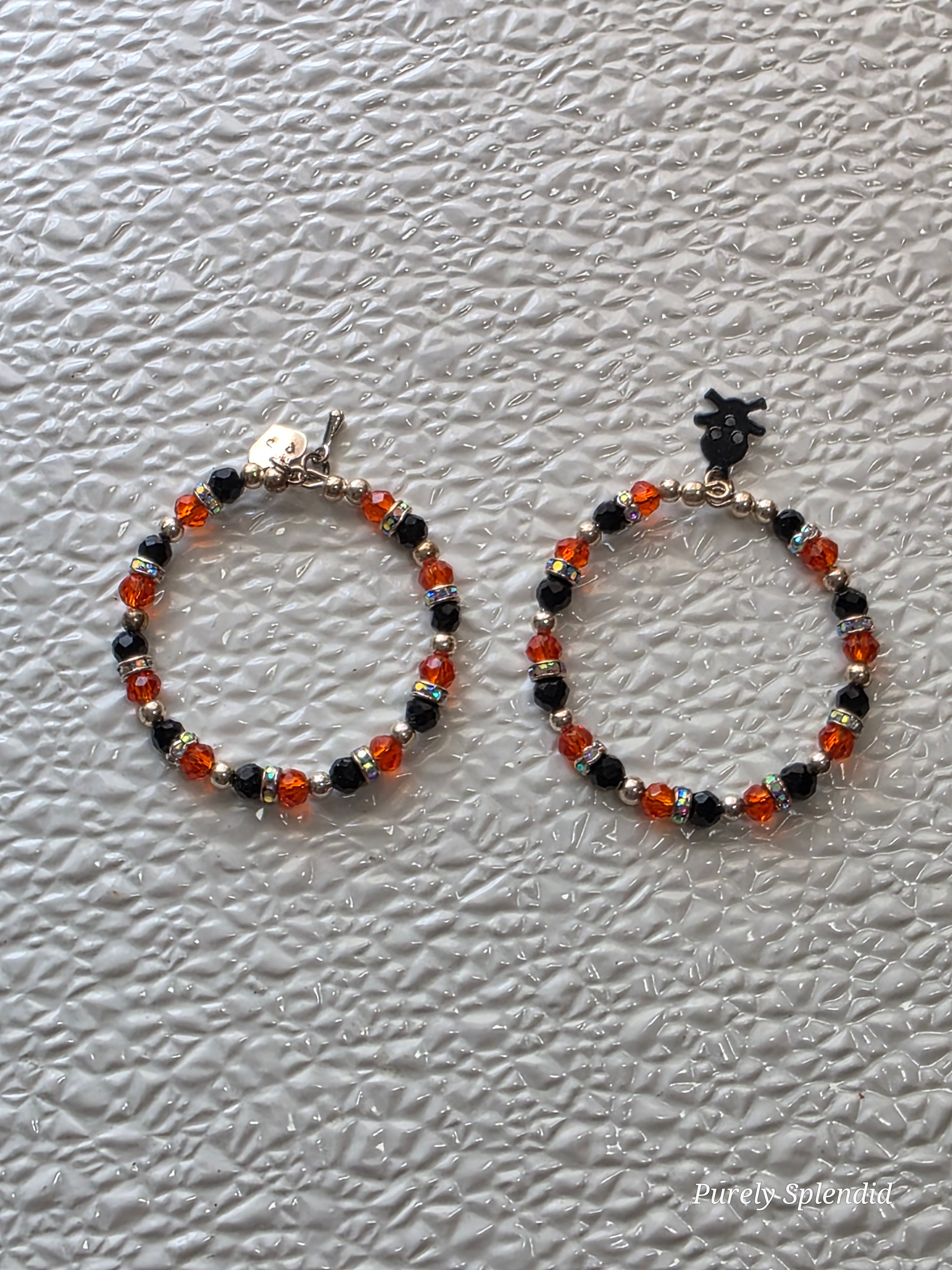 Sparkling Orange and Black Halloween Charm Bracelets one with a black skull and crossbones charm