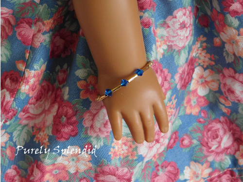 three blue colored crystals highlighted on a gold colored bangle bracelet