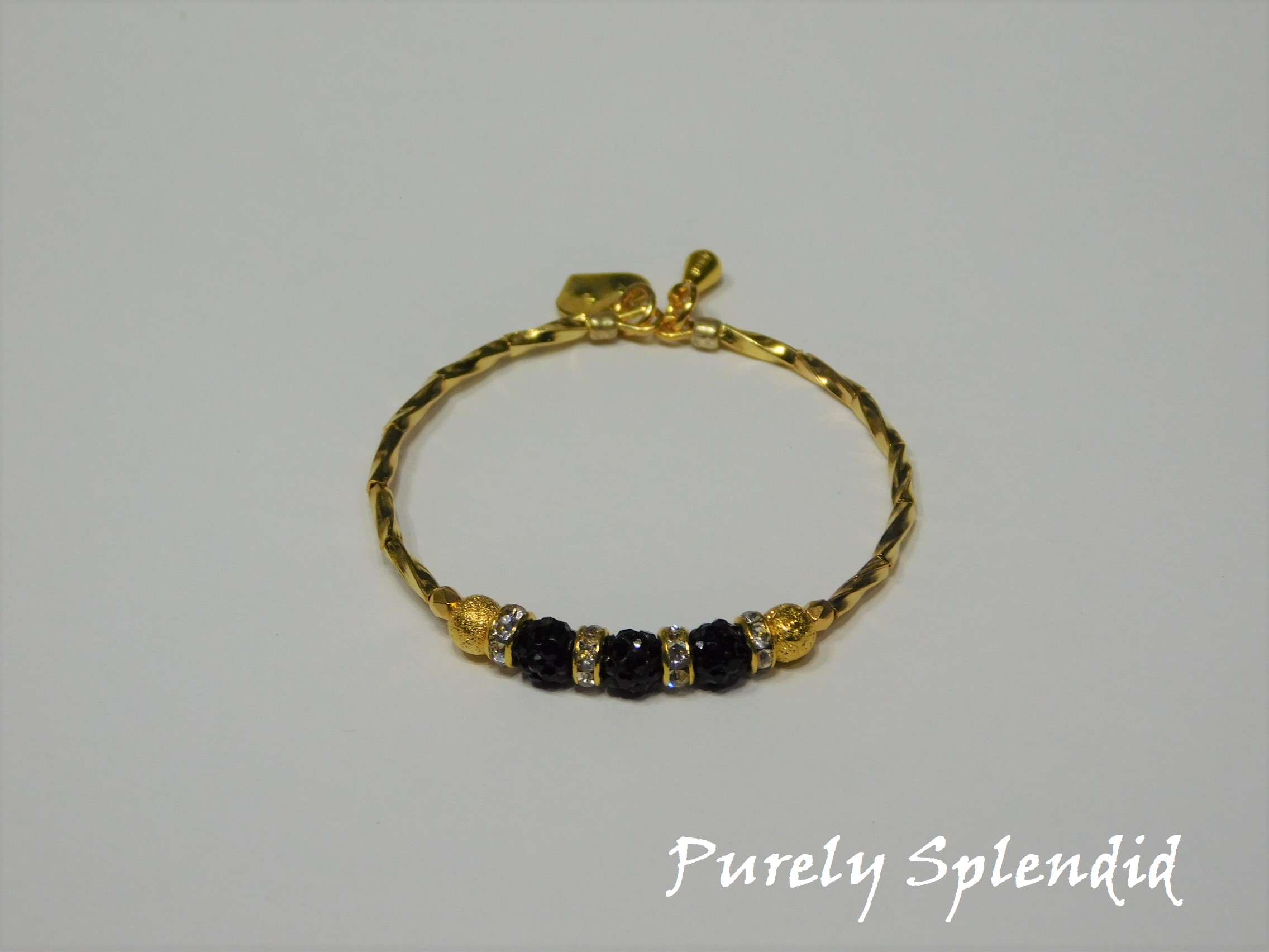Gold bracelet with three round sparkling black beads each surrounded with a ring of sparkle