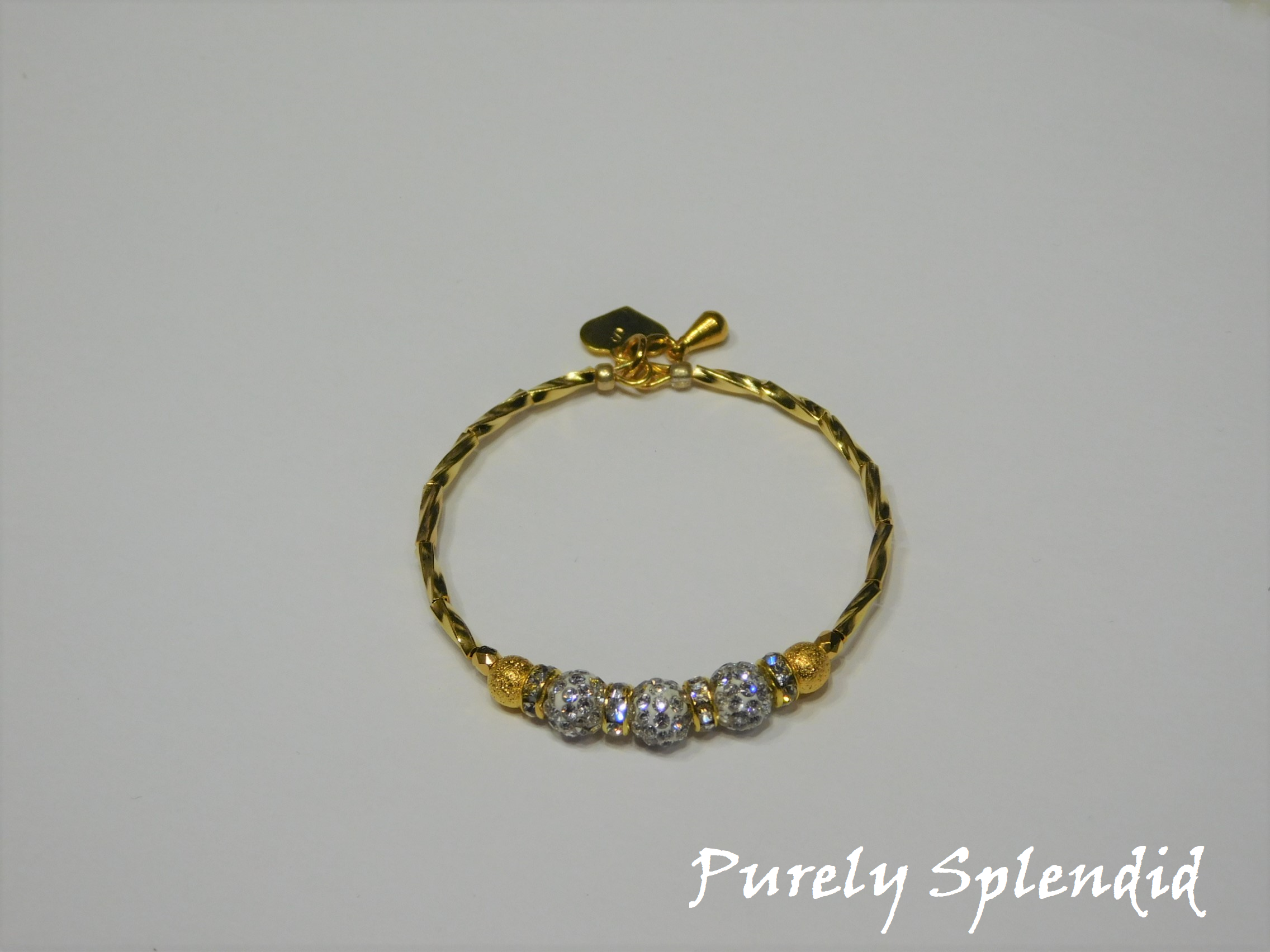 Gold bracelet with three round sparkling silver beads each surrounded with a ring of sparkle