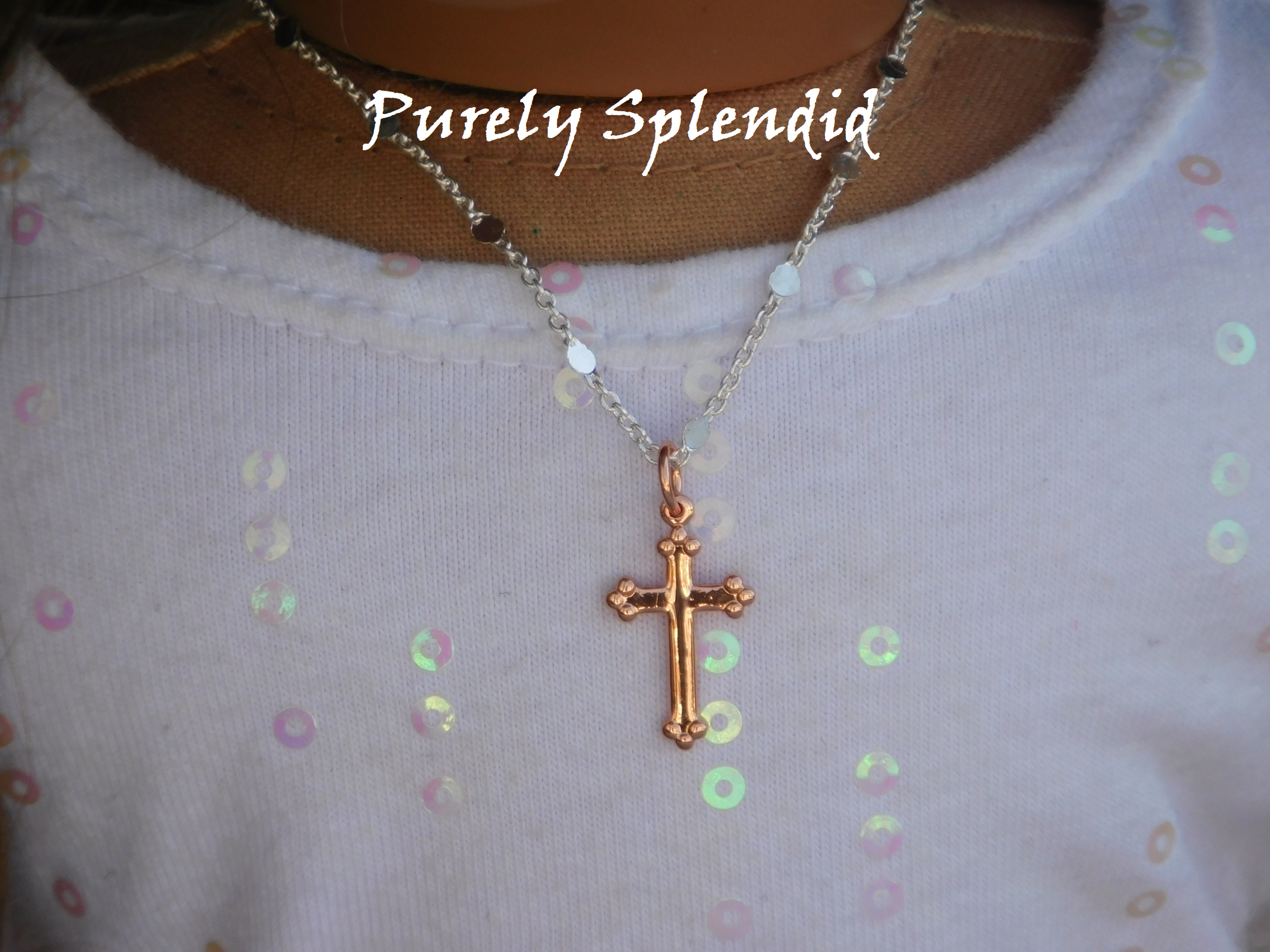 decorative rose gold cross on a decorative silver chain shown worn by an 18 inch doll