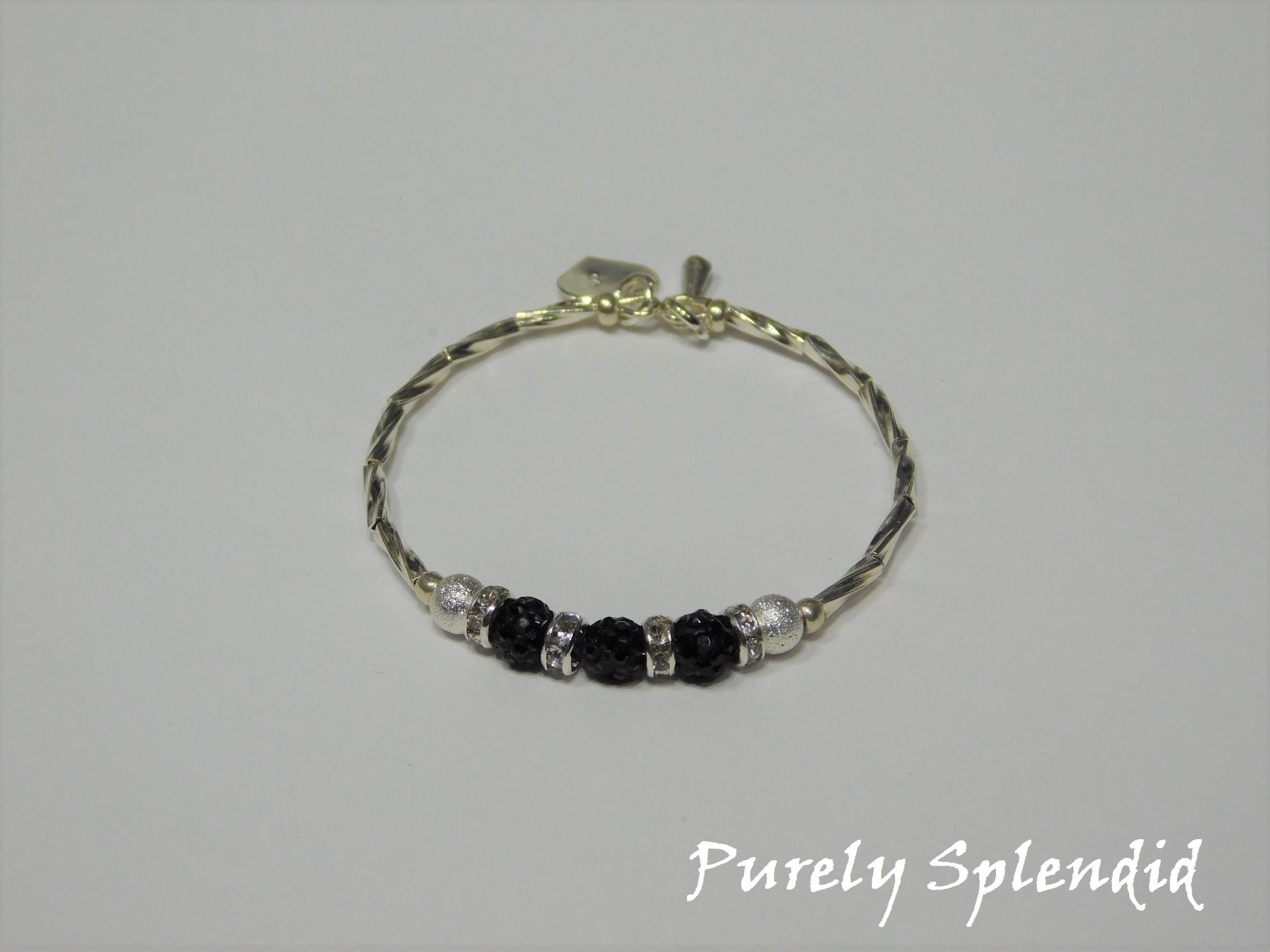 Silver bracelet with three round sparkling black beads each surrounded with a ring of sparkle