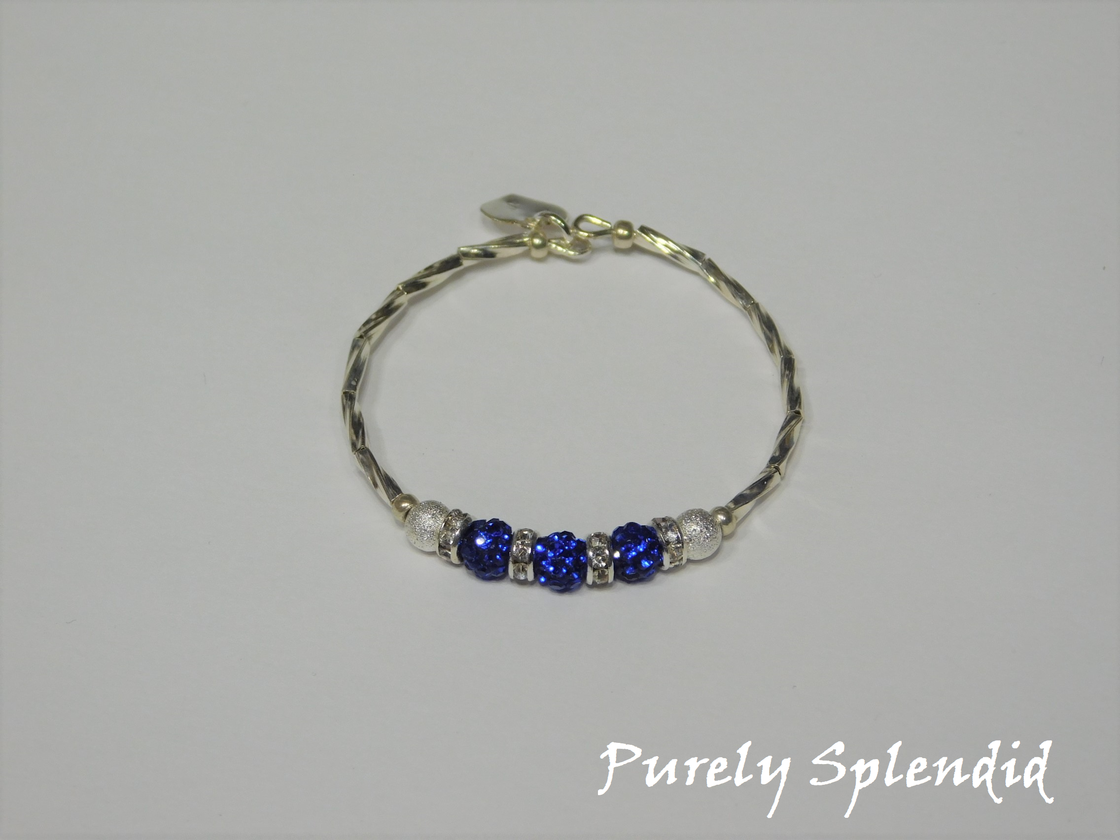 Silver bracelet with three round sparkling blue beads each surrounded with a ring of sparkle