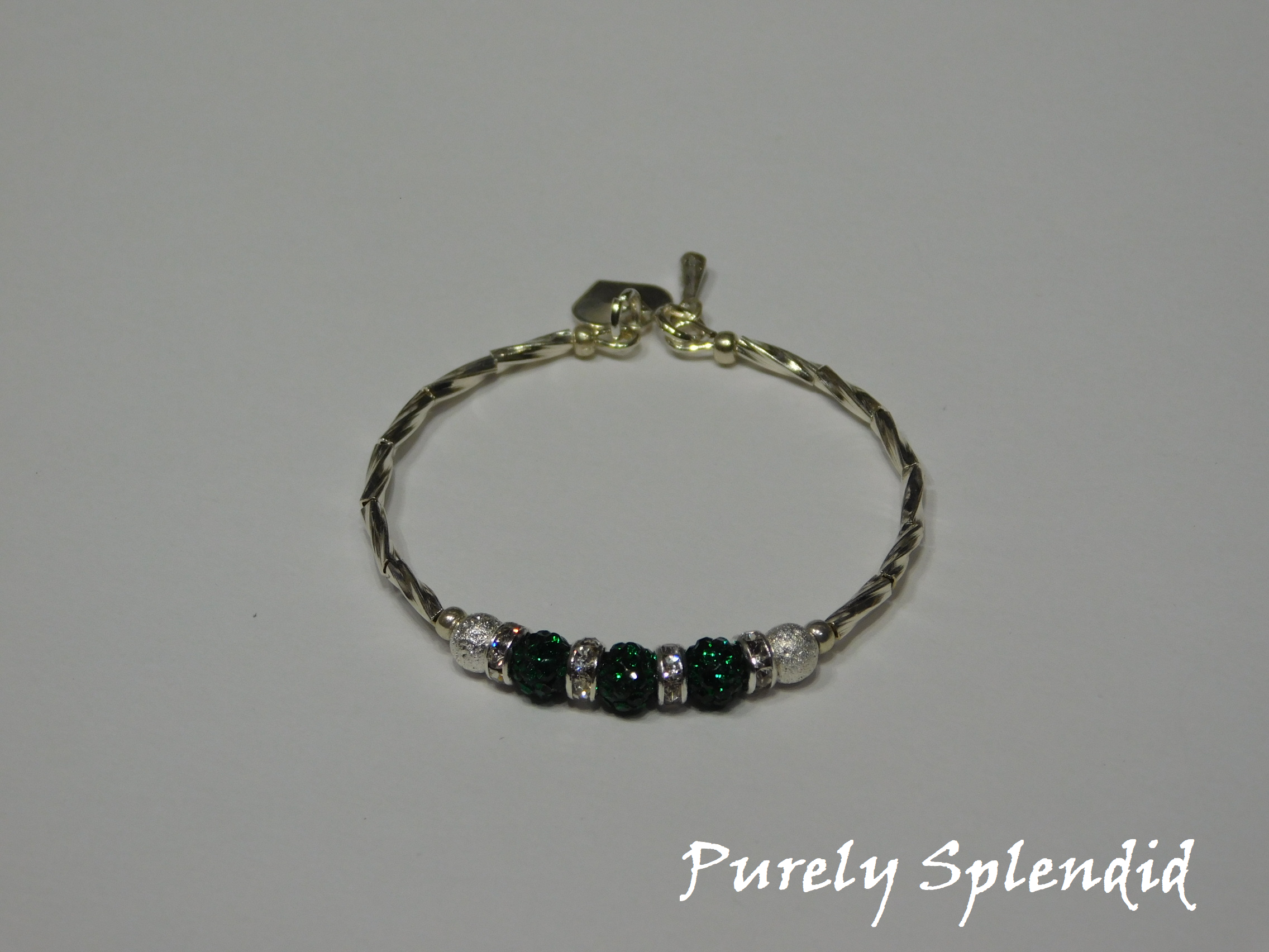 Silver bracelet with three round sparkling green beads each surrounded with a ring of sparkle