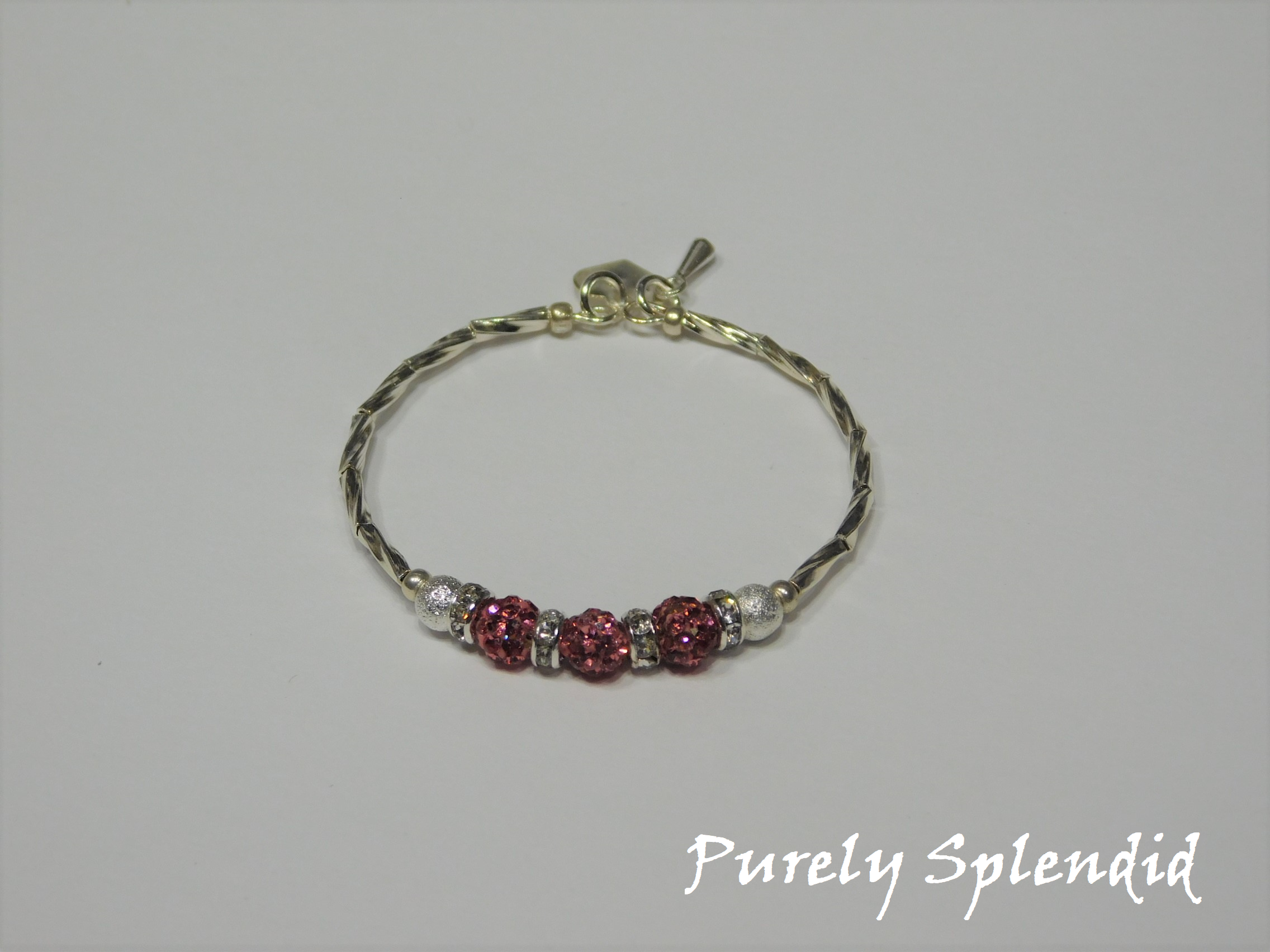 Silver bracelet with three round sparkling pink beads each surrounded with a ring of sparkle