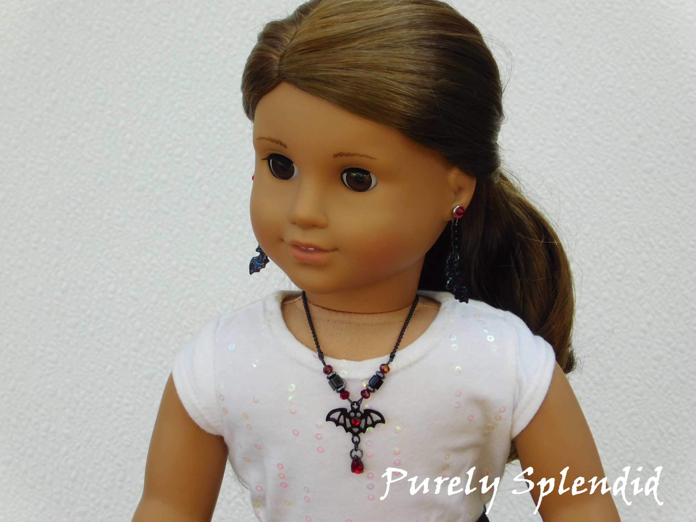 black bat necklace with red accents worn by an 18 inch doll