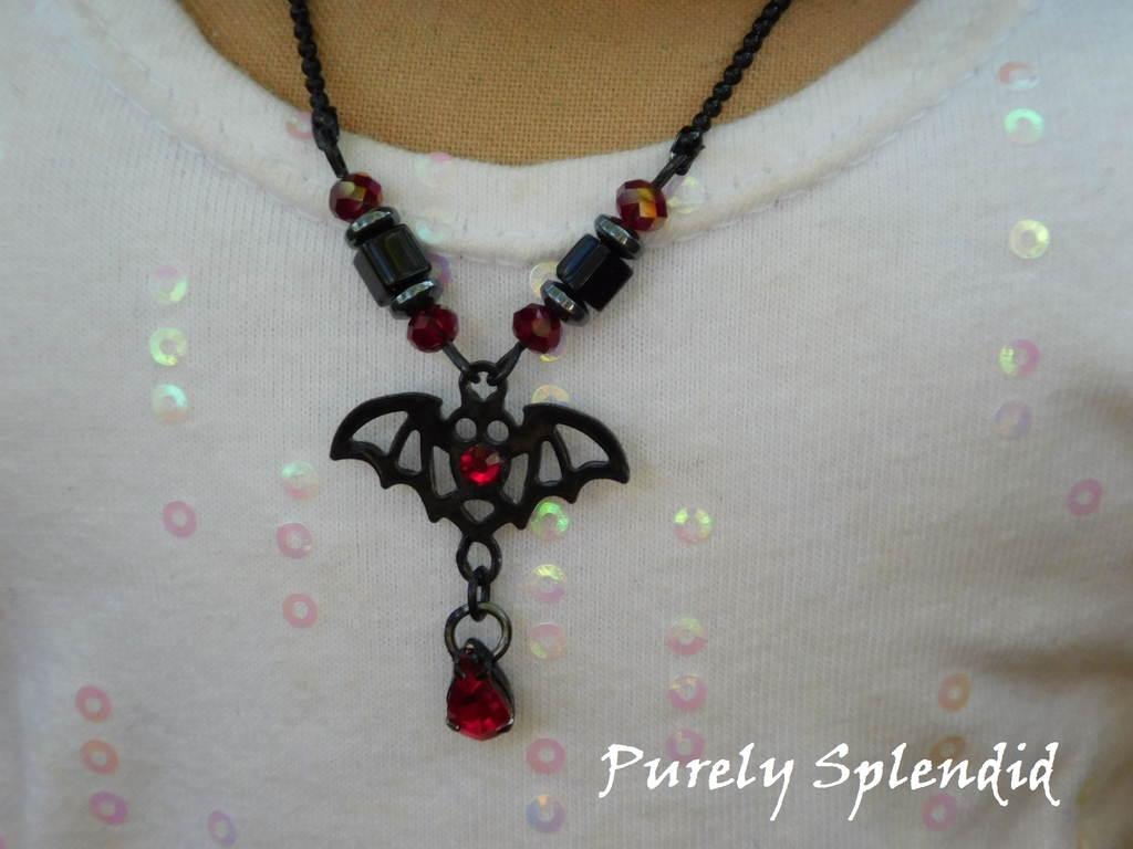 black bat necklace with red accents shown on an 18 inch doll