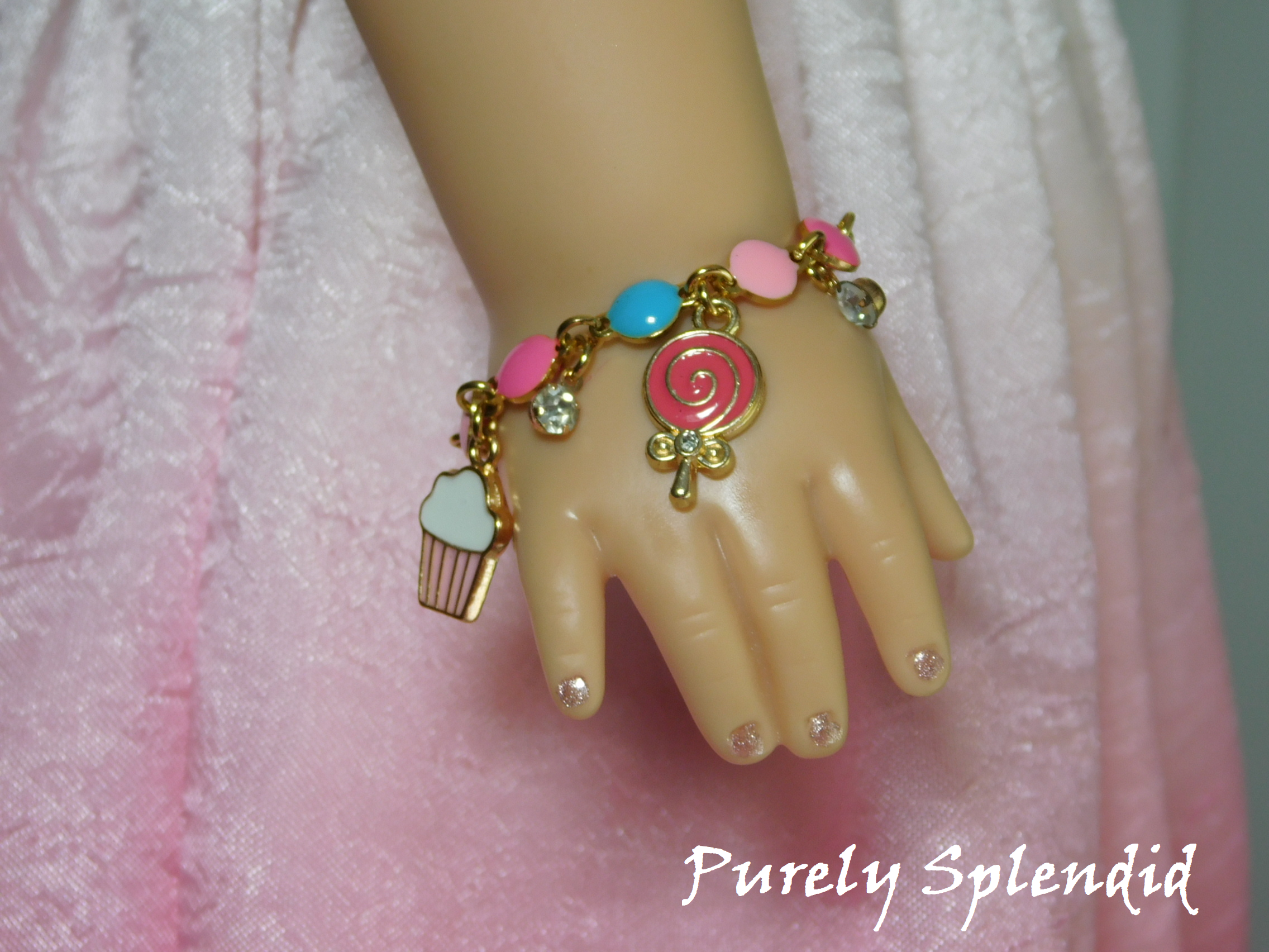 18 inch doll shown wearing the Birthday Charm Bracelet with cupcake, candy and sparkling charms.
