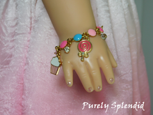 Load image into Gallery viewer, 18 inch doll shown wearing the Birthday Charm Bracelet with cupcake, candy and sparkling charms.
