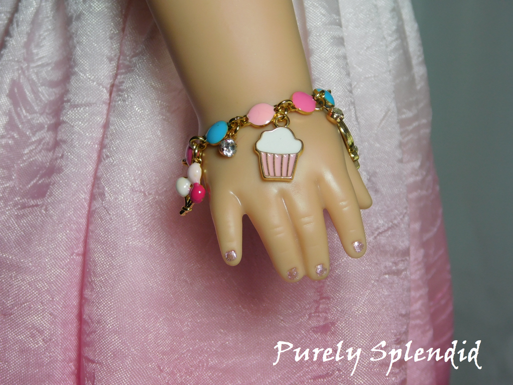18 inch doll shown wearing a festive Birthday Charm Bracelet shown with balloons, cupcake and sparkling charms