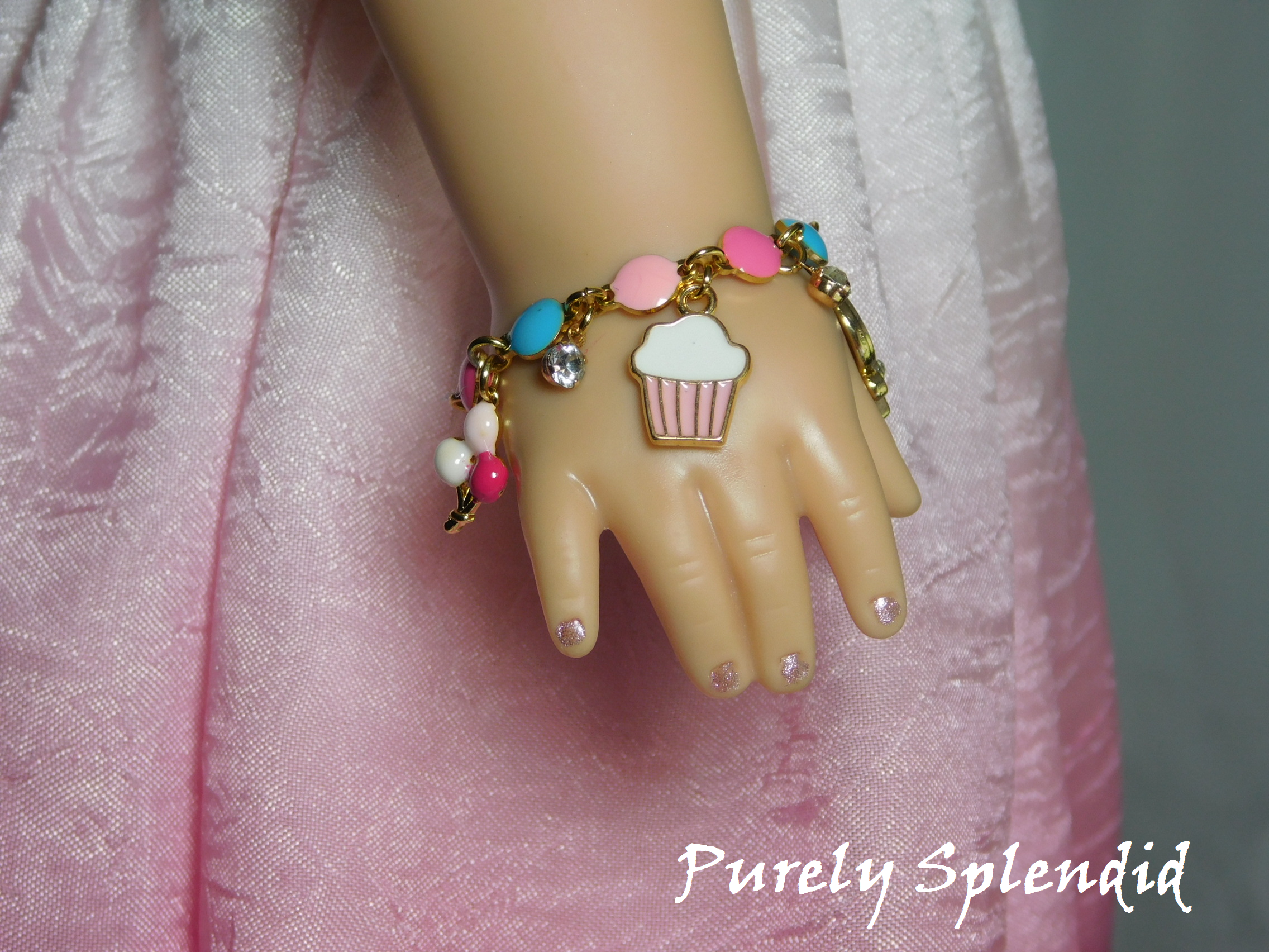 18 inch doll shown wearing a festive Birthday Charm Bracelet shown with balloons, cupcake and sparkling charms