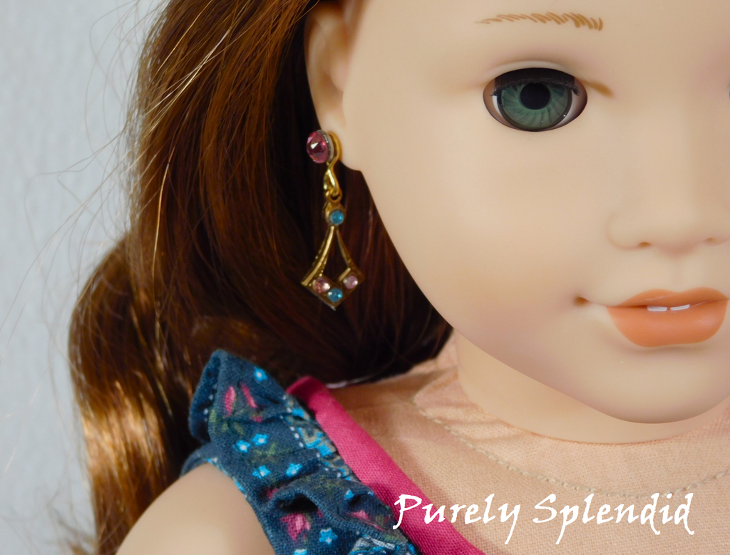 18 inch doll shown wearing a pair of Create Your Own Sparkling Earrings with light blue and light pink crystals