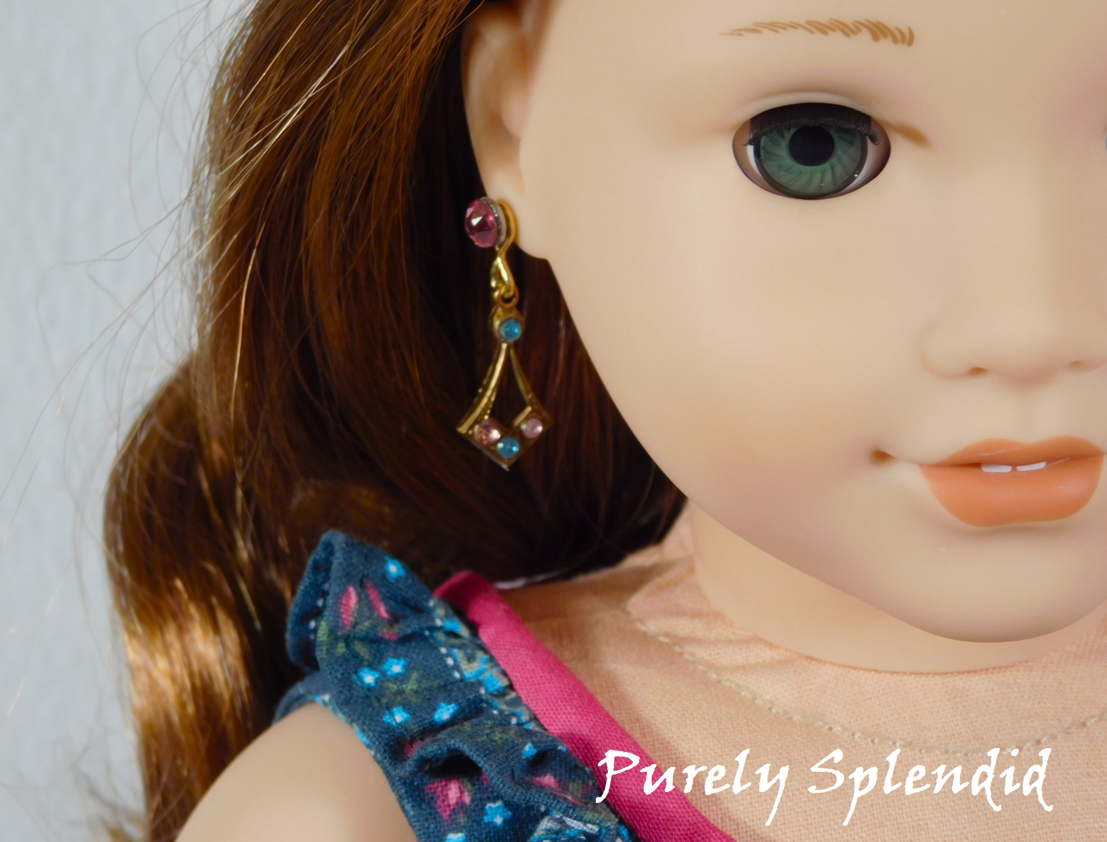 18 inch doll shown wearing a pair of Create Your Own Sparkling Earrings with light blue and light pink crystals