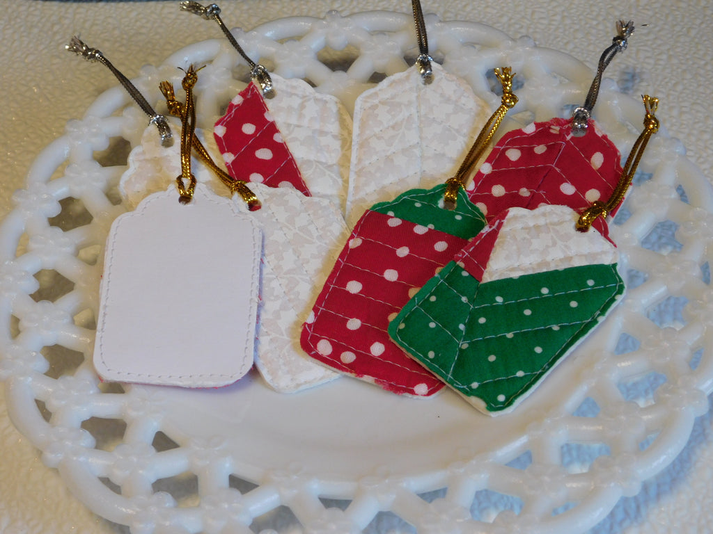 8 fabric gift tags with a card stock back. Each has either a gold or silver metallic hanger. Fabric is a bright green with white dots, bright red with random white dots and a white on white floral, all which has been quilted