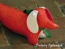 Load image into Gallery viewer, dachshund made with red fabric with gold dots, light beige ears and under body wearing a sparkling green bow around the neck and a silver heart dangling from it
