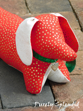 Load image into Gallery viewer, dachshund made of red fabric with gold dots and light beige ears and under body wearing a sparking green bow around the neck which has a silver heart hanging from it

