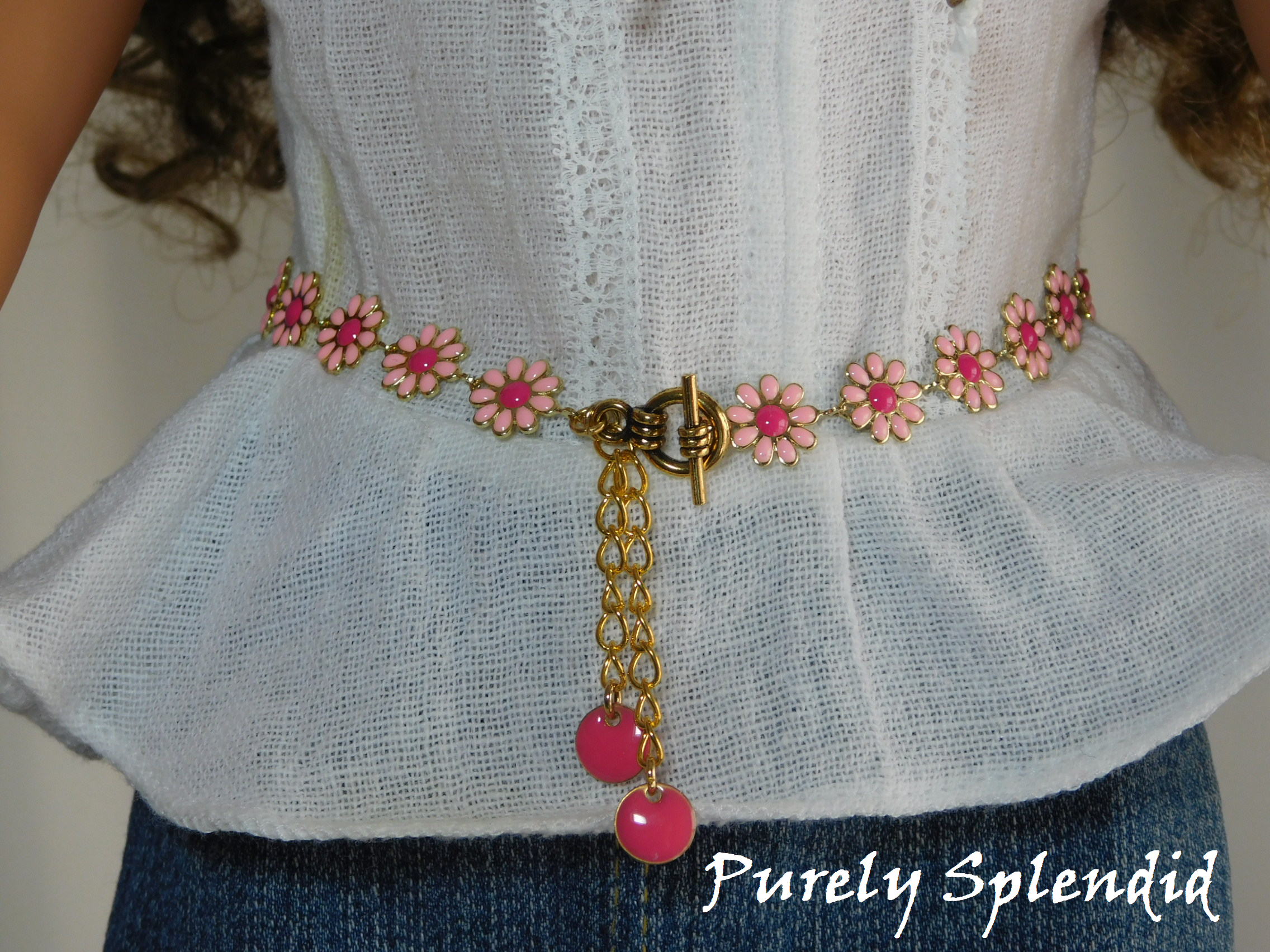 18 inch doll shown wearing a Daisy Belt with light pink flowers, dark pink centers and dark pink dangles. Fastens with a toggle clasp
