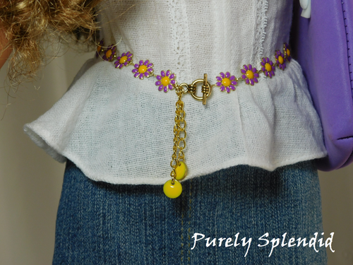 18 inch doll shown wearing a Daisy Belt with purple flowers, yellow centers and yellow dangles. Fastens with a toggle clasp