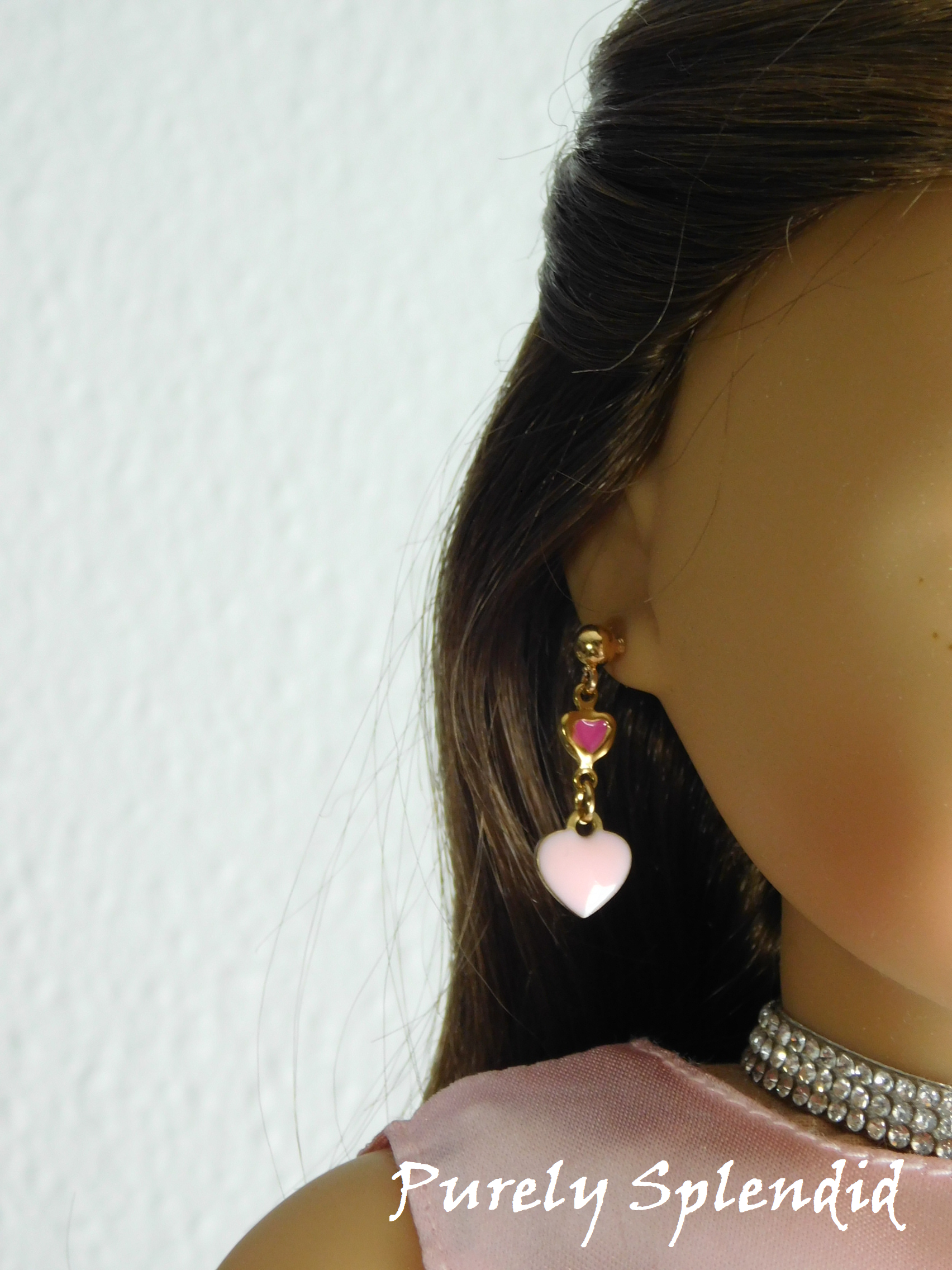 18 inch doll wearing a pair of White Double Heart Earrings - one tiny dark pink heart with a larger white heart hanging below it