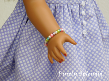 Load image into Gallery viewer, 18 inch doll shown wearing the colorful Easter Pearl Bracelet made up of glass pearls
