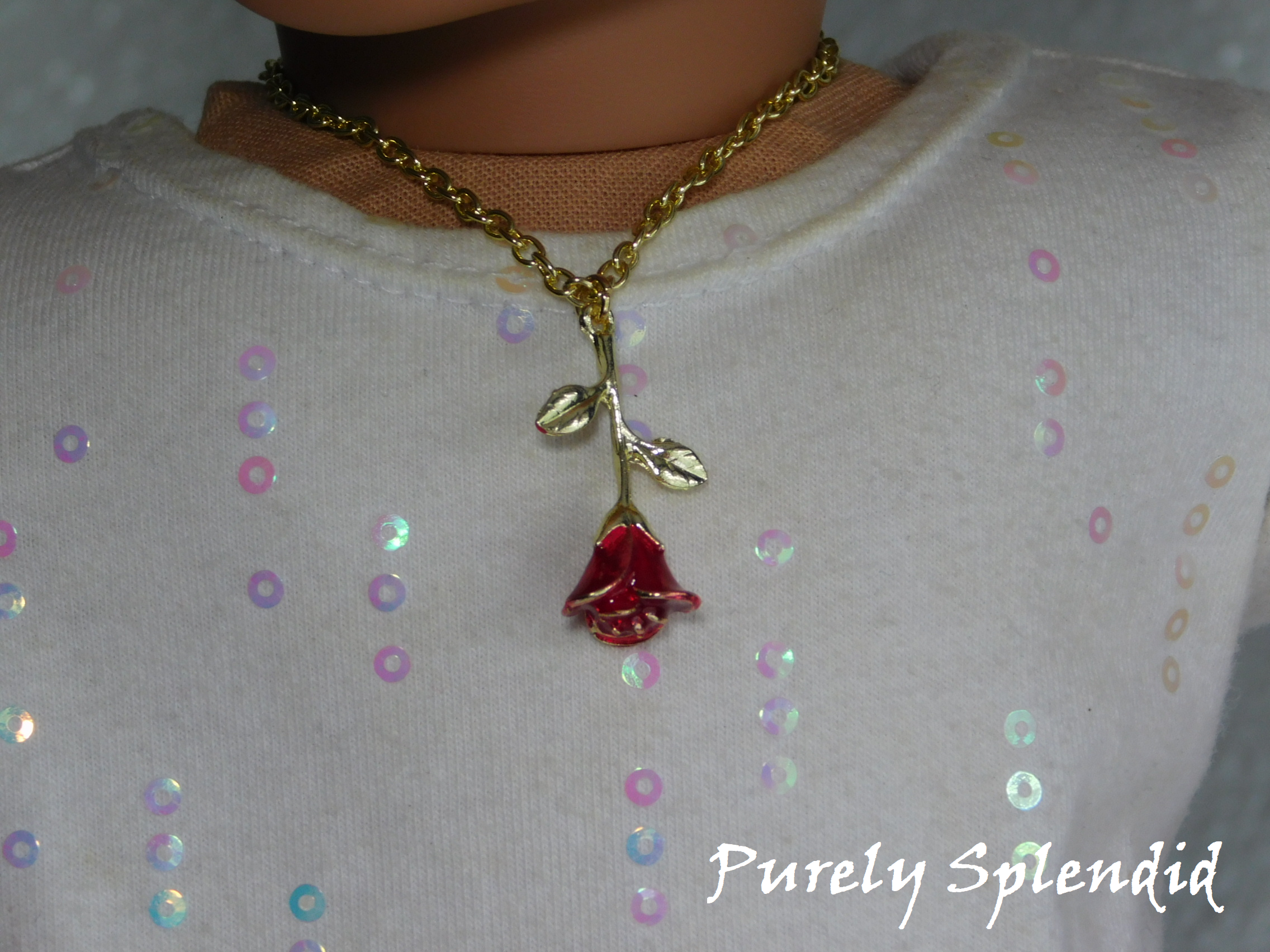 gold tipped rose hanging upside down on a gold chain worn by an 18 inch doll