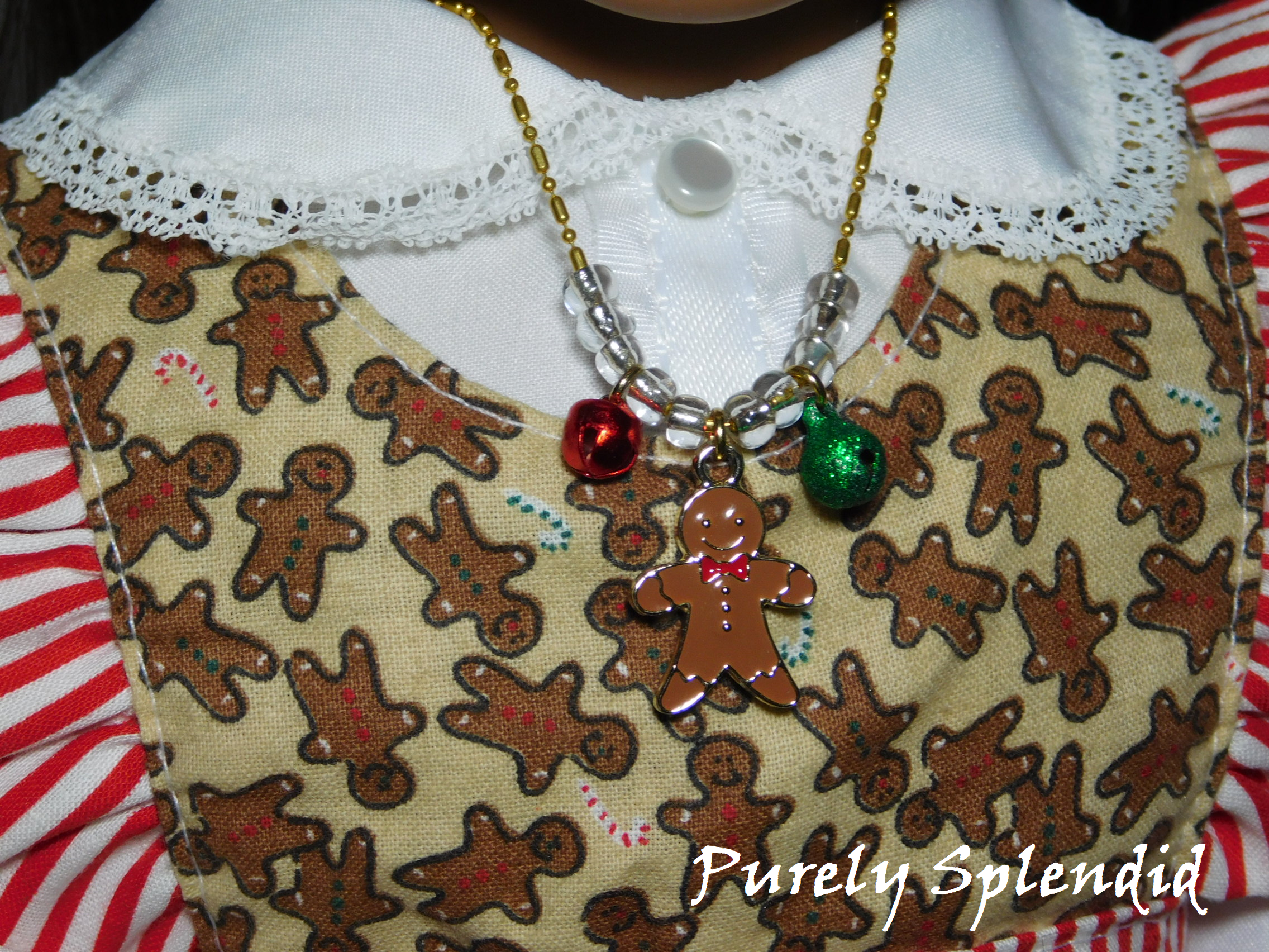 gingerbread man charm on a gold chain with clear beads and one red and one green jingle bell on either side of the gingerbread man