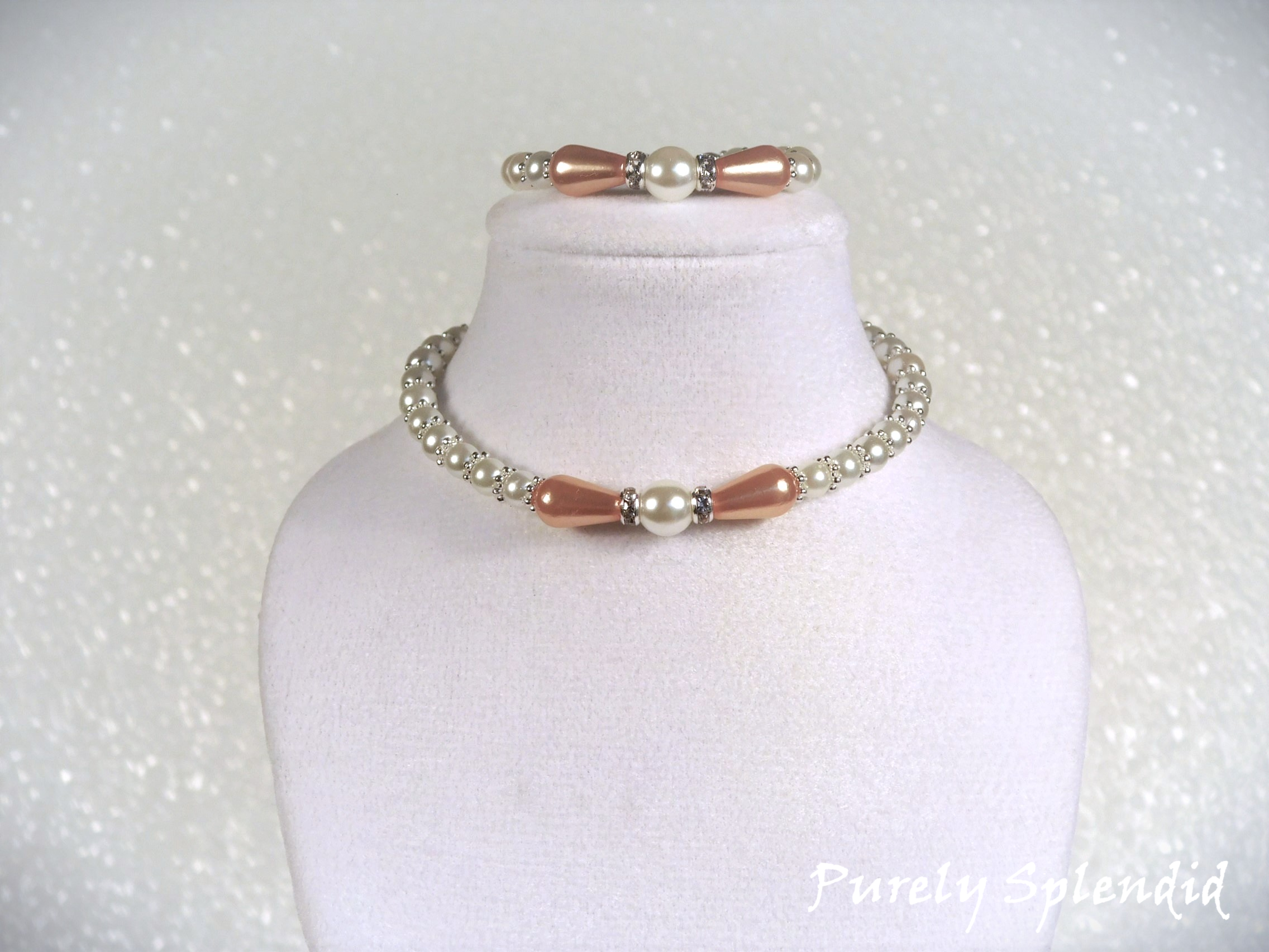 peachy colored teardrop pearls surround a white round center pearl which is the focal point of this white pearl necklace and bracelet for 18 inch dolls