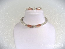 Load image into Gallery viewer, peachy colored teardrop pearls surround a white round center pearl which is the focal point of this white pearl necklace and bracelet for 18 inch dolls
