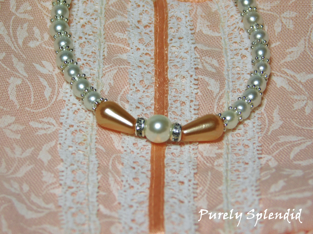 Peaches n Pearl Necklace with two teardrop shaped peach colored pearls set around a large round white pearl which is the focal point of a white pearl necklace