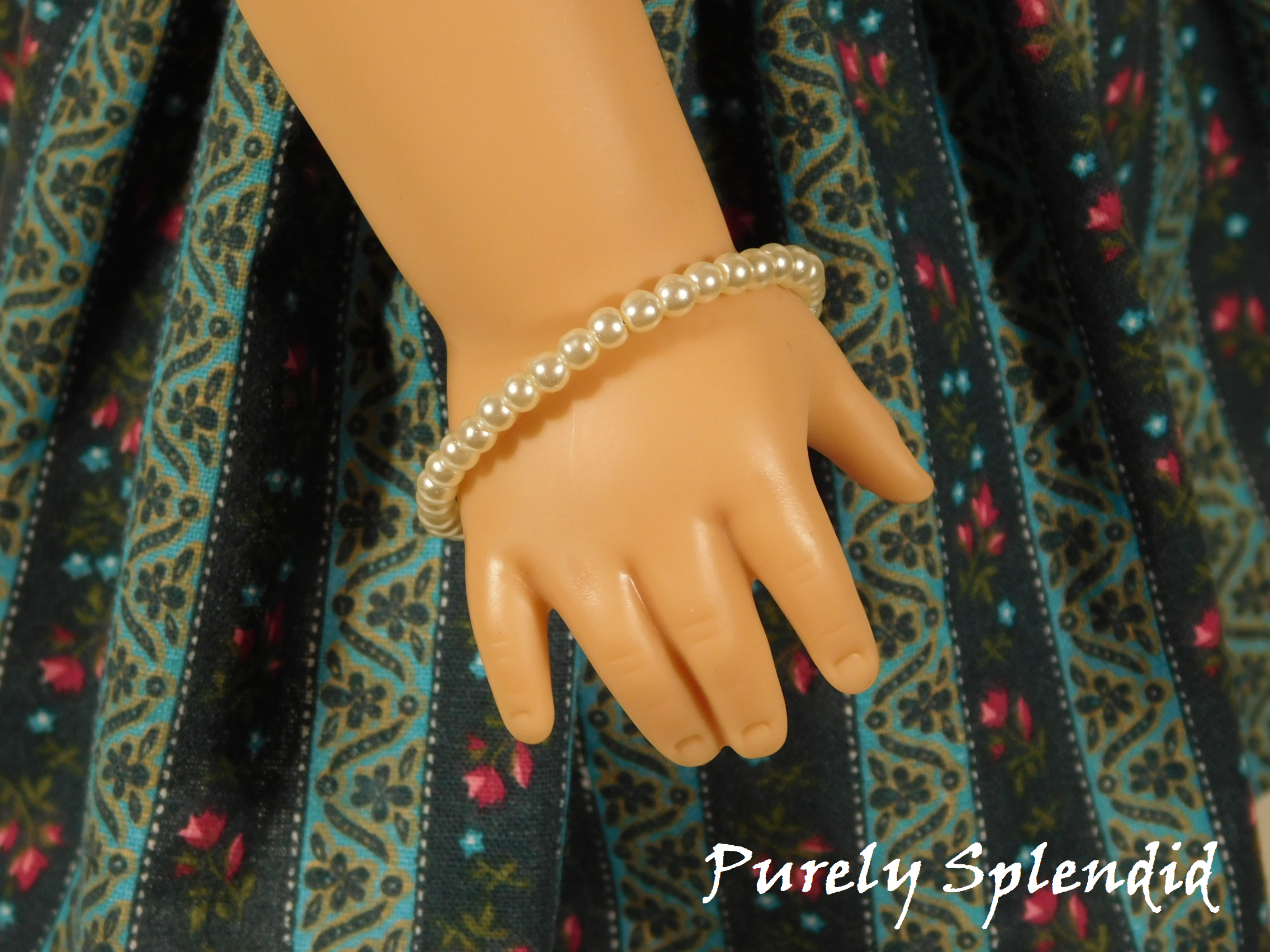 single row of white pearls stacking bracelet shown worn by an 18 inch doll