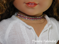 a row of Aurora Borealis rhinestones on either side of a row of pink rhinestones as a choker necklace worn by an 18 inch doll