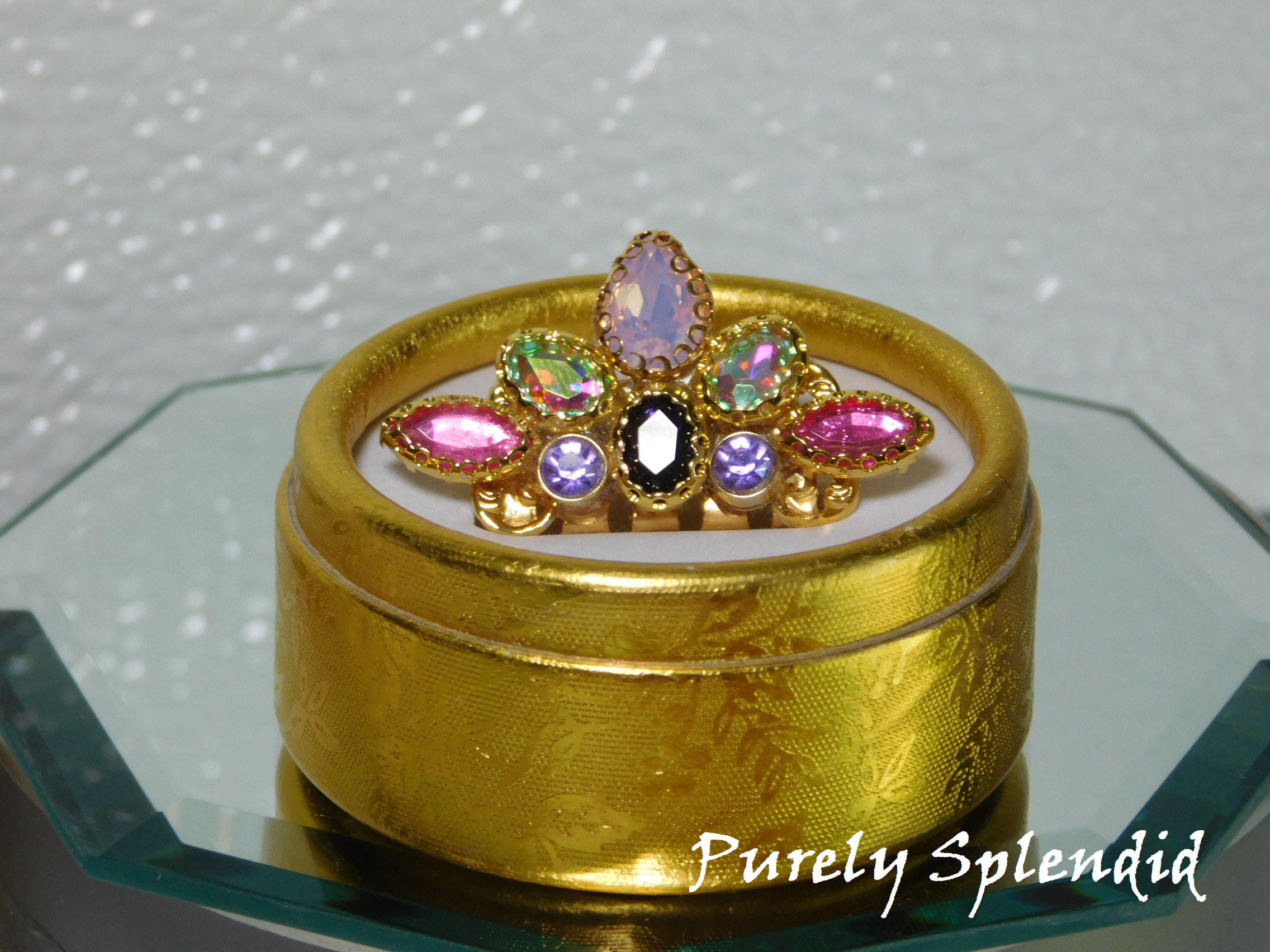 beautiful jeweled mini crown with pink, purple, opal and aurora borealis stones. shown in a gold gift box