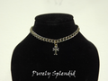 heavy silver chain with a cross charm hanging from shown on a doll mannequin
