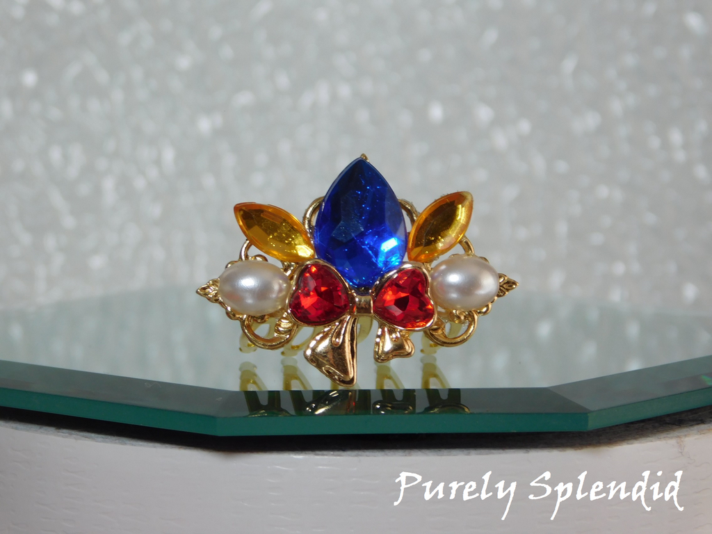 Snow White Crown for dolls with a large blue center stone, sparkling red bow with white pearls on either side of it
