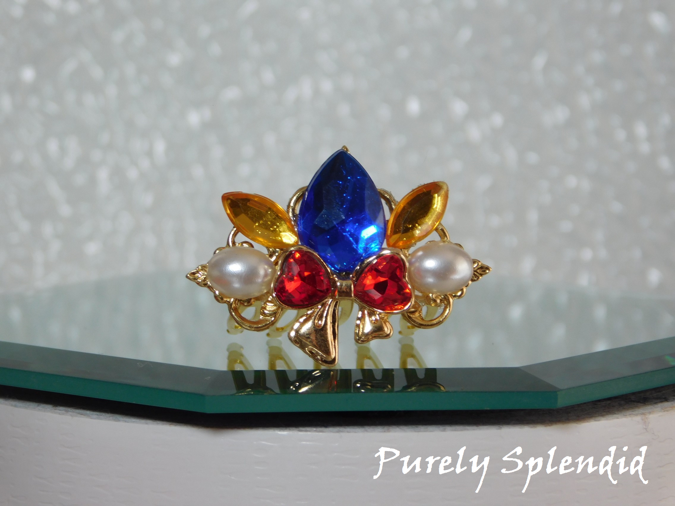 Snow White Crown for dolls with a large blue center stone, sparkling red bow with white pearls on either side of it