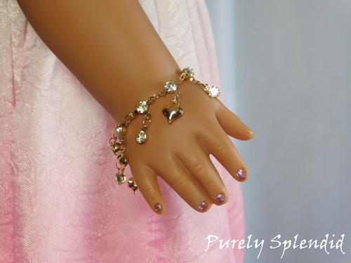 puffy gold heart charms and sparking rhinestone drops on a sparkling gold bracelet shown worn by an 18 inch doll