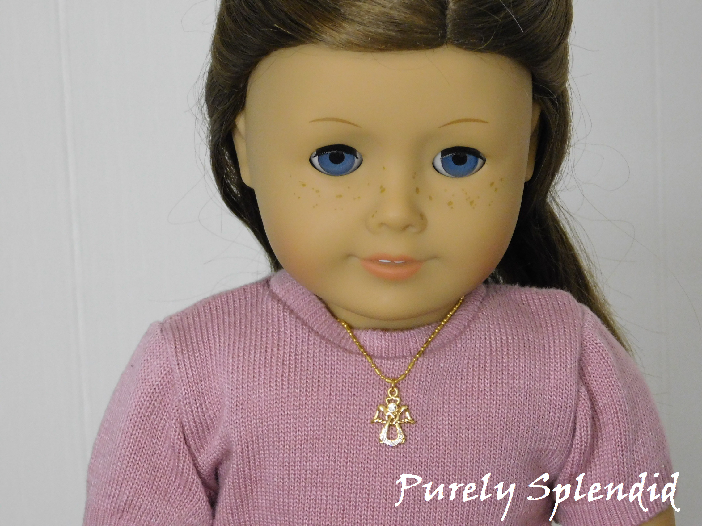 18 inch doll wearing a sparkling gold angel on a gold chain