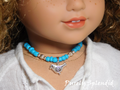 18 inch doll shown wearing a blue and silver beaded necklace with a silver bird pendant