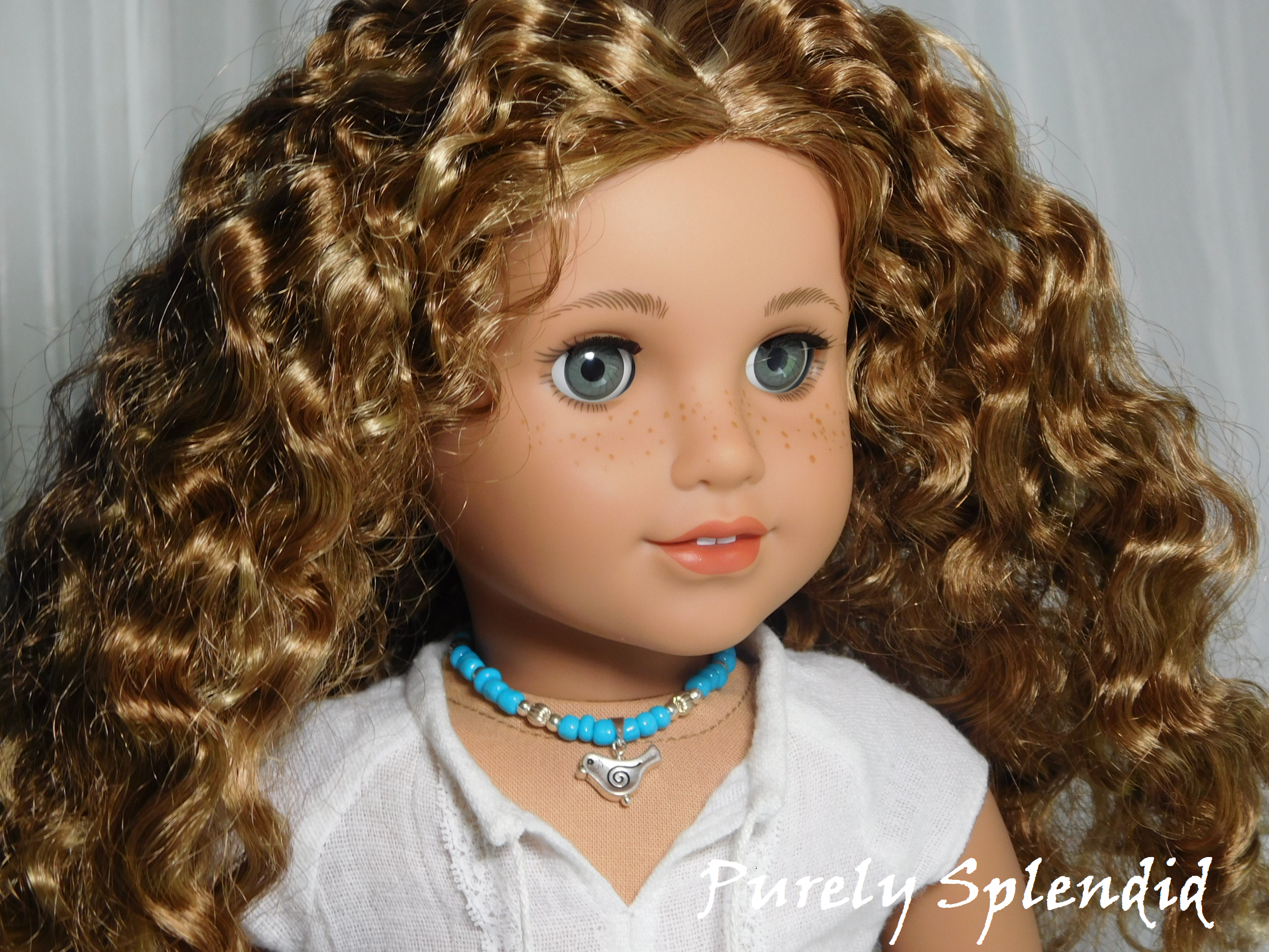18 inch doll shown wearing a blue and silver beaded necklace with a silver bird pendant