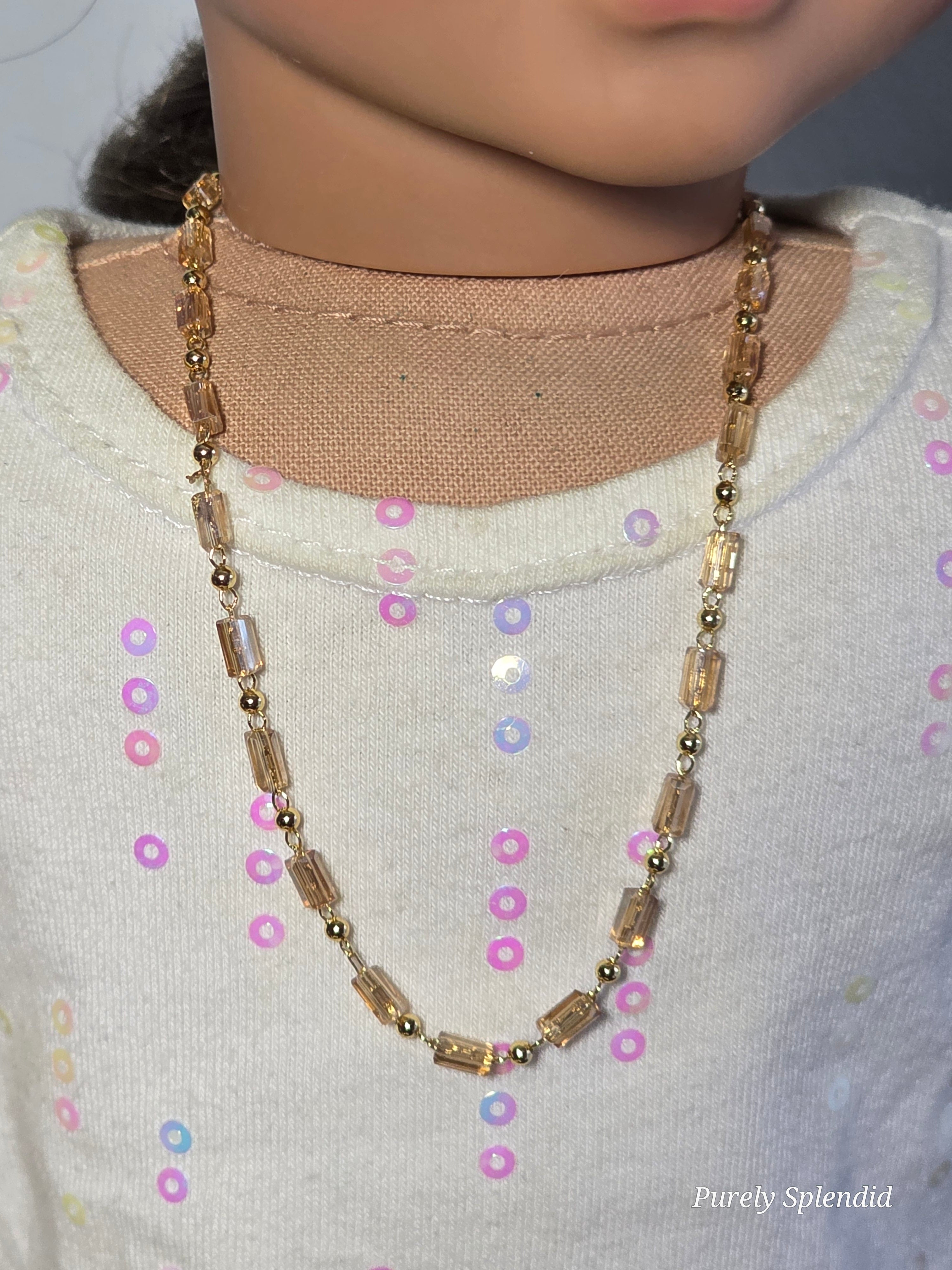 long crystal necklace with gold beads worn by an 18 inch doll