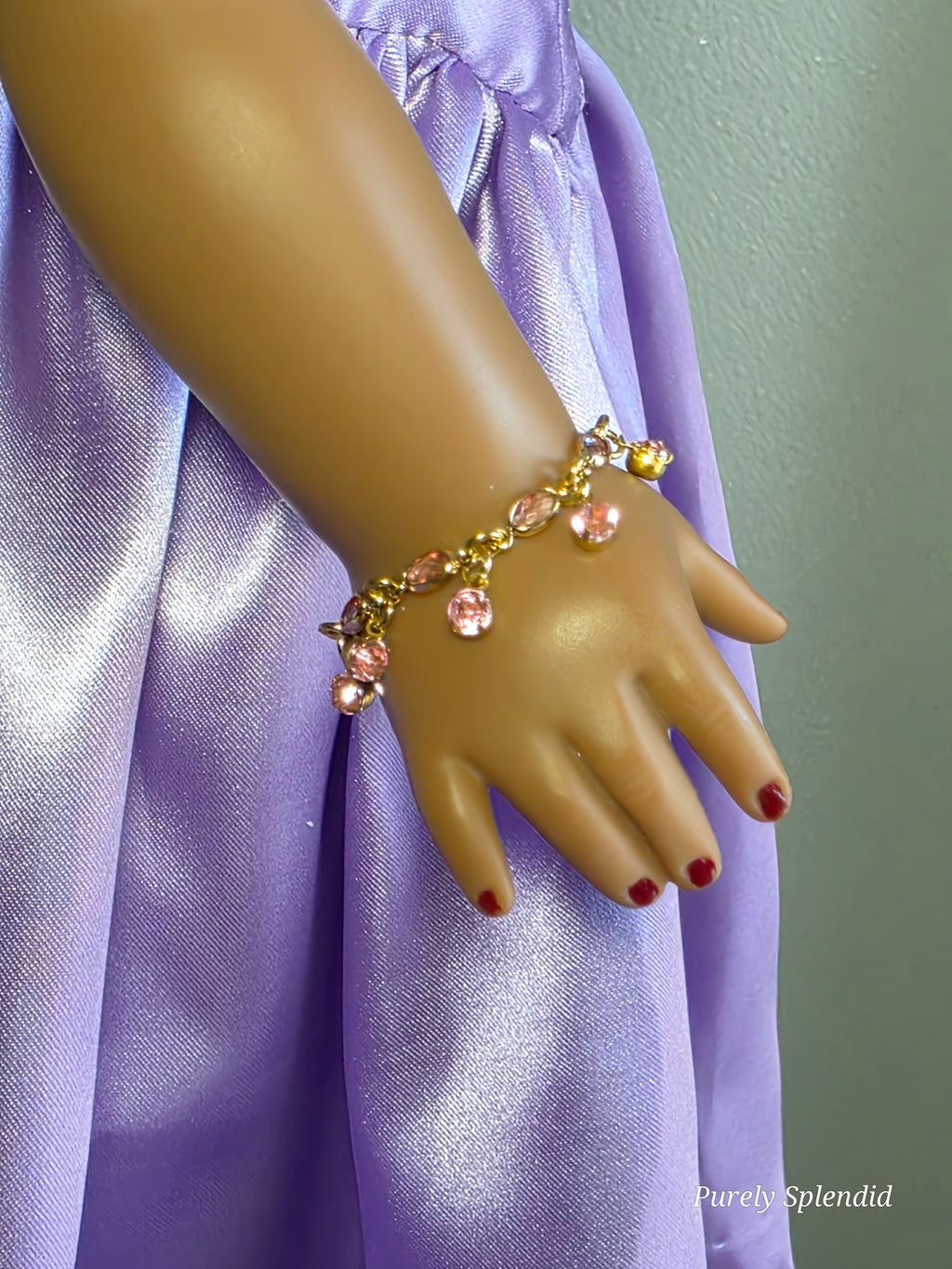 18 inch doll wearing pink bracelet with pink dangles