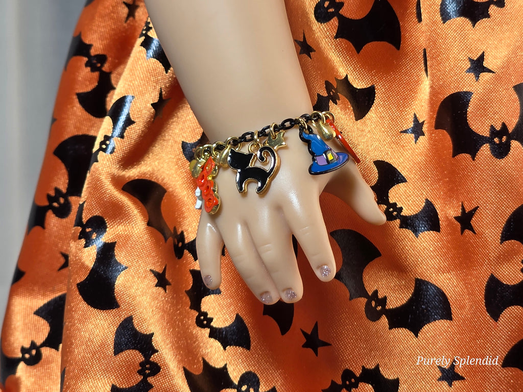 18 inch doll wearing a Halloween charm bracelet with black cat and witches hat charms