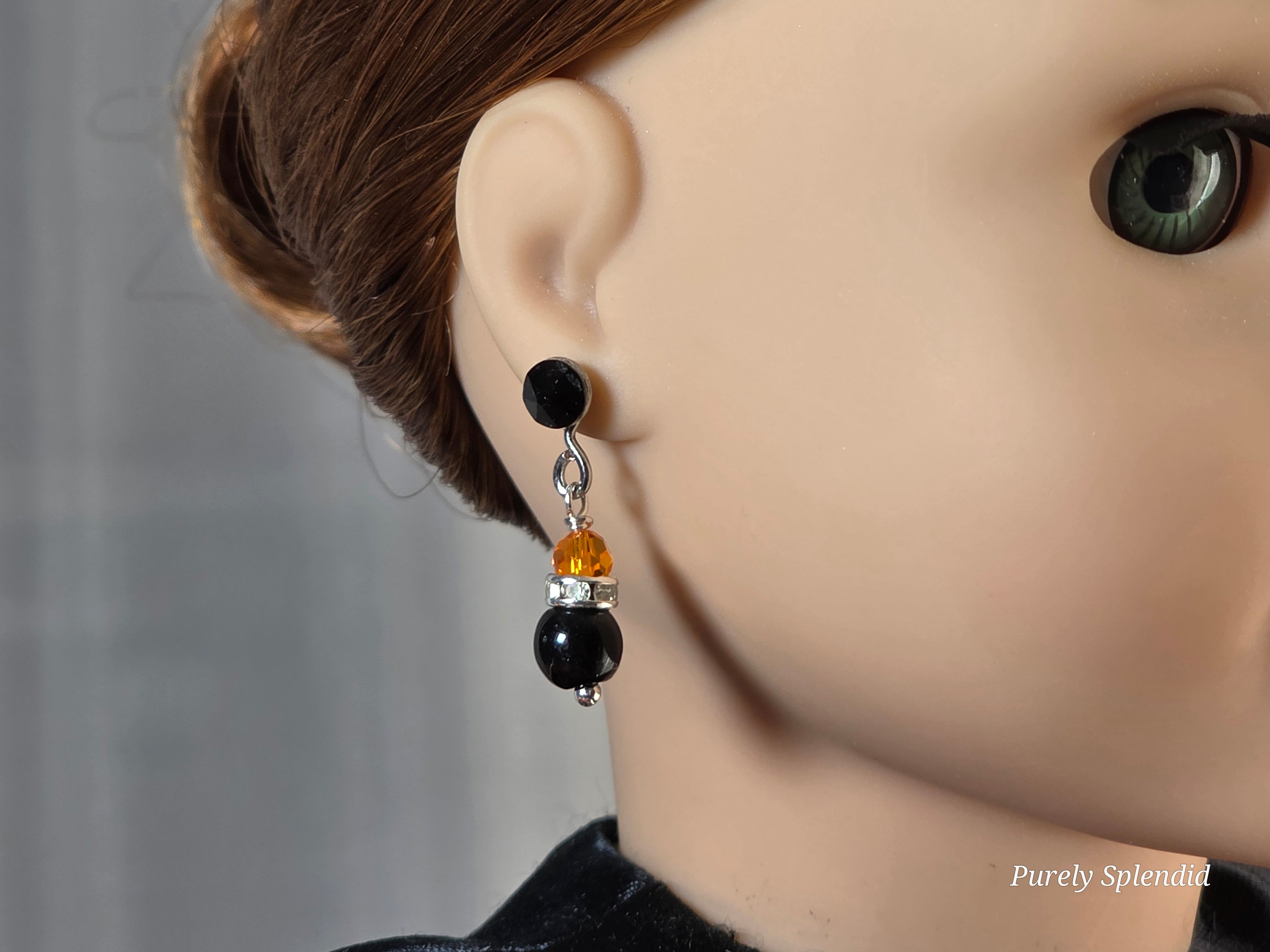 Doll wearing a pair of Sparkling Halloween Earrings and Jet Black 2mm Studs