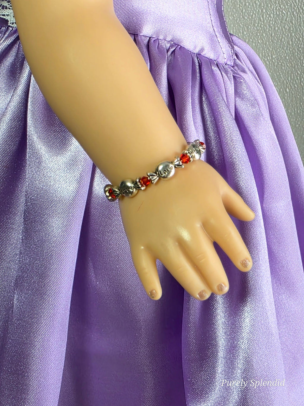 18 inch doll wearing Valentine candy bracelet with the word love on the candy