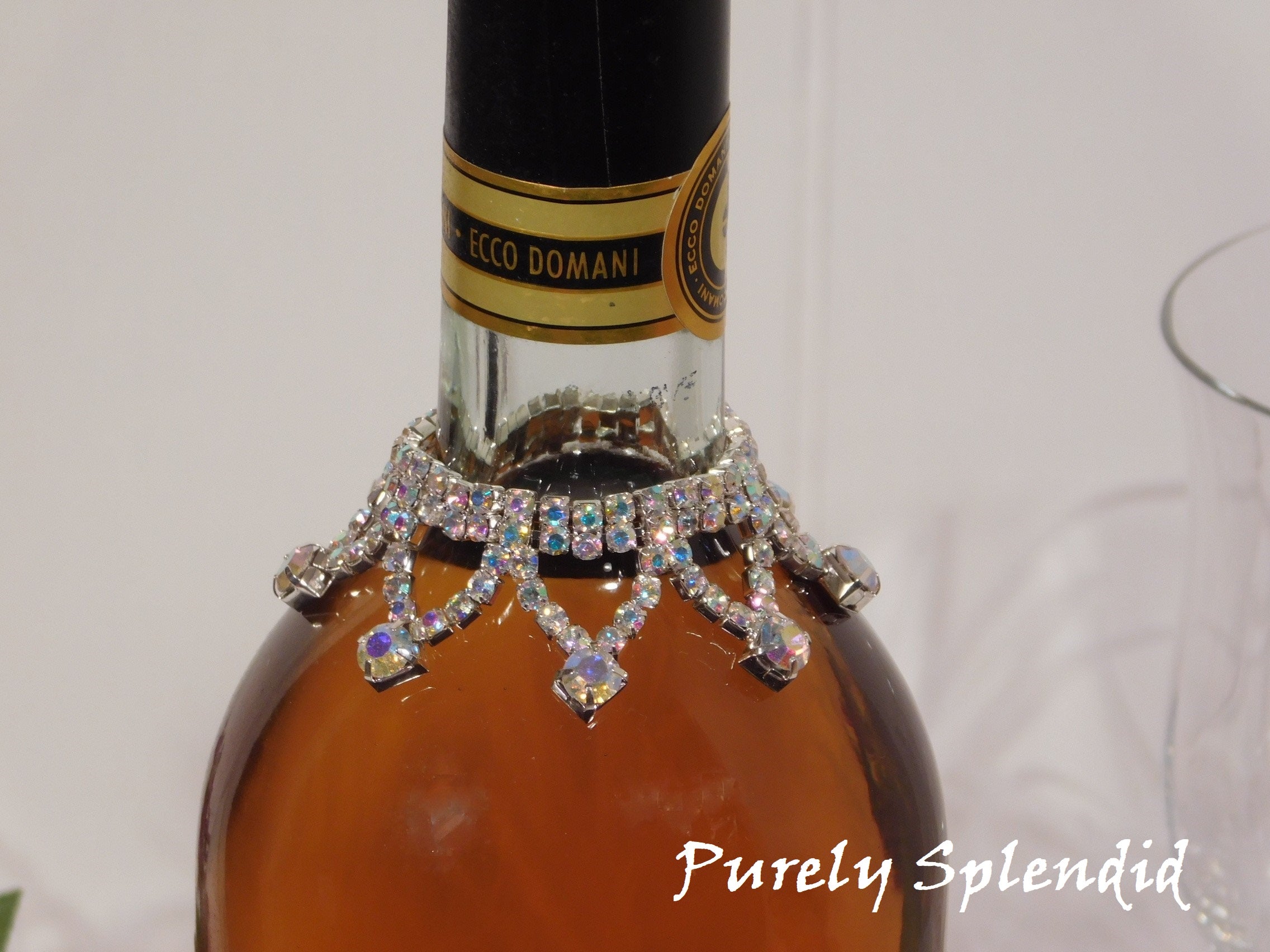 close up of the Sparkling Aurora Borealis Wine Bottle Bline Necklace shown on a standard size white wine bottle