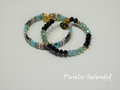 two black and blue colored stacking bracelets one with flat beads and the other with shaped crystals